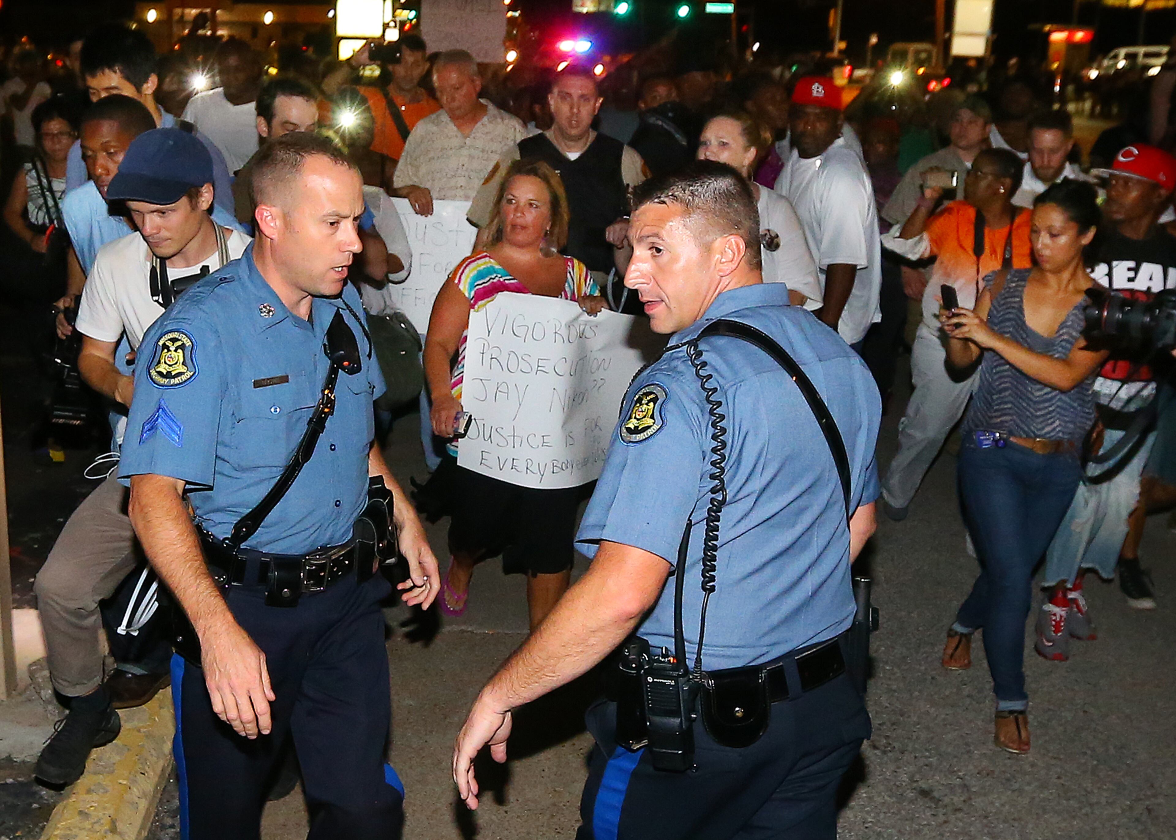 A woman who identified herself only as Dawn (center) causes a near riot walking down West Floressant Avenue with a sign of support for police officer Darren Wilson, named as the shooter of Michael Brown. She drew a crowd of protesters on Wednesday, August 20, 2014, in Ferguson. Police had to rescue the woman with an extraction vehicle and call in a SWAT team to disperse a crowd that began to grow out of control. CURTIS COMPTON / CCOMPTON@AJC.COM