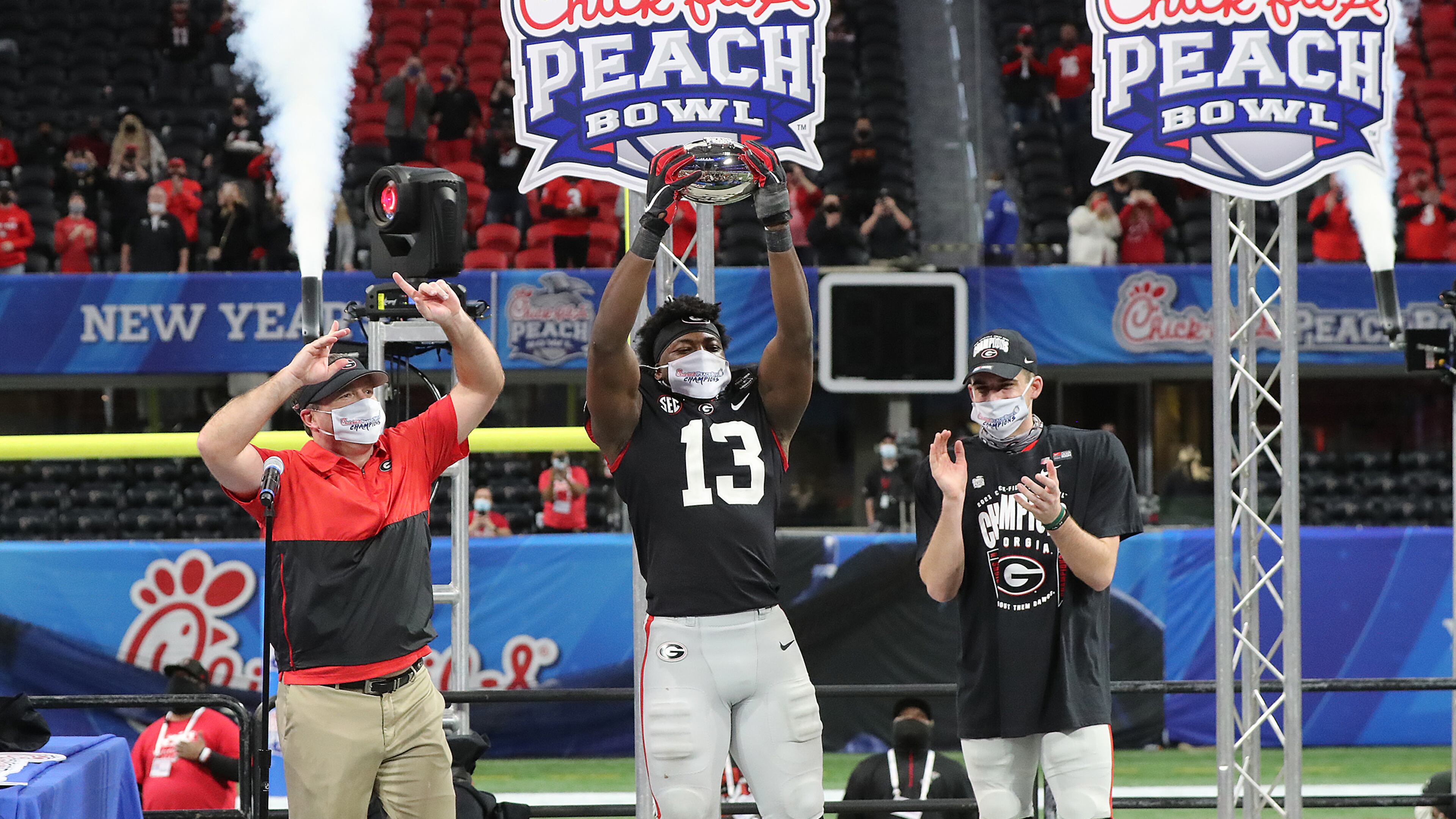 010121 ATLANTA: Georgia head coach Kirby Smart (from left), defensive player of the game Azeez Ojulari hoisting the trophy, and quarterback JT Daniels celebrate beating Cincinnati 24-21 in the NCAA college football Peach Bowl game on Friday, Jan. 1, 2021, in Atlanta. Curtis Compton / Curtis.Compton@ajc.com”