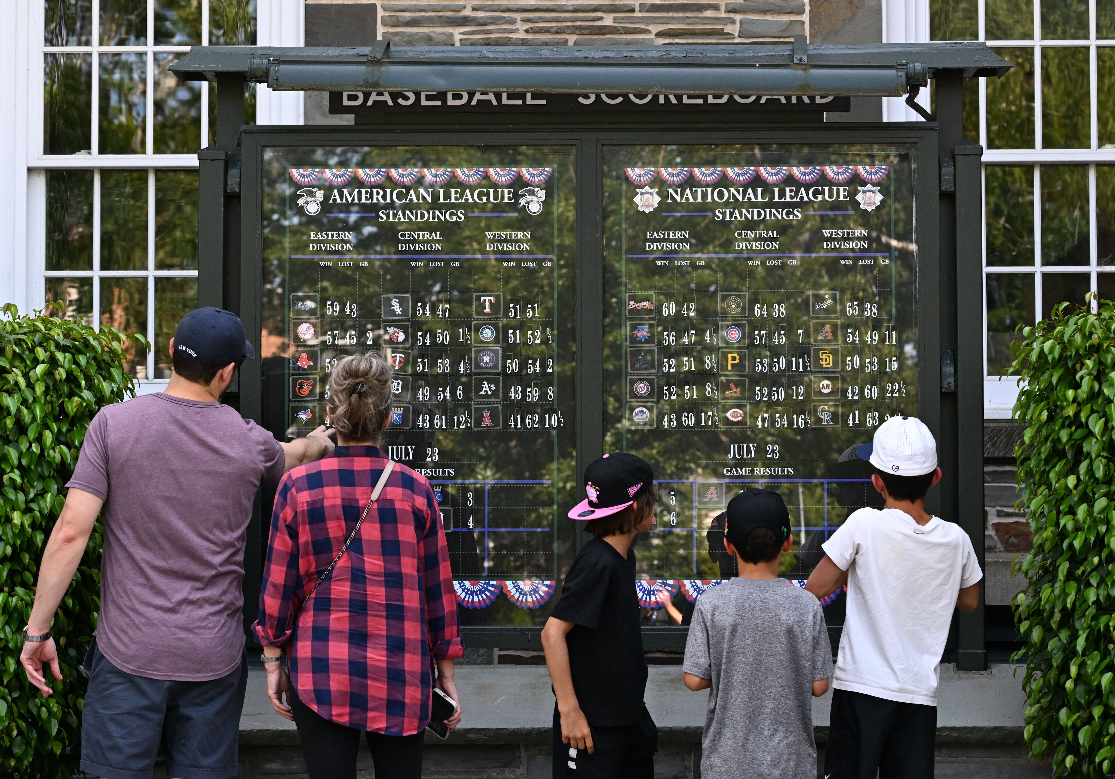 Baseball fans check out the baseball scoreboard outside the National Baseball Hall of Fame and Museum on Friday, July 24, 2026, in Cooperstown, N.Y. Andruw Jones will be inducted into the National Baseball Hall of Fame on Sunday as part of the Class of 2026, alongside Carlos Beltrán and Jeff Kent. He is recognized as one of the greatest center fielders in baseball history. Jones will become the 12th player with ties to the Atlanta Braves to be inducted into the Hall of Fame. (Hyosub Shin/AJC)