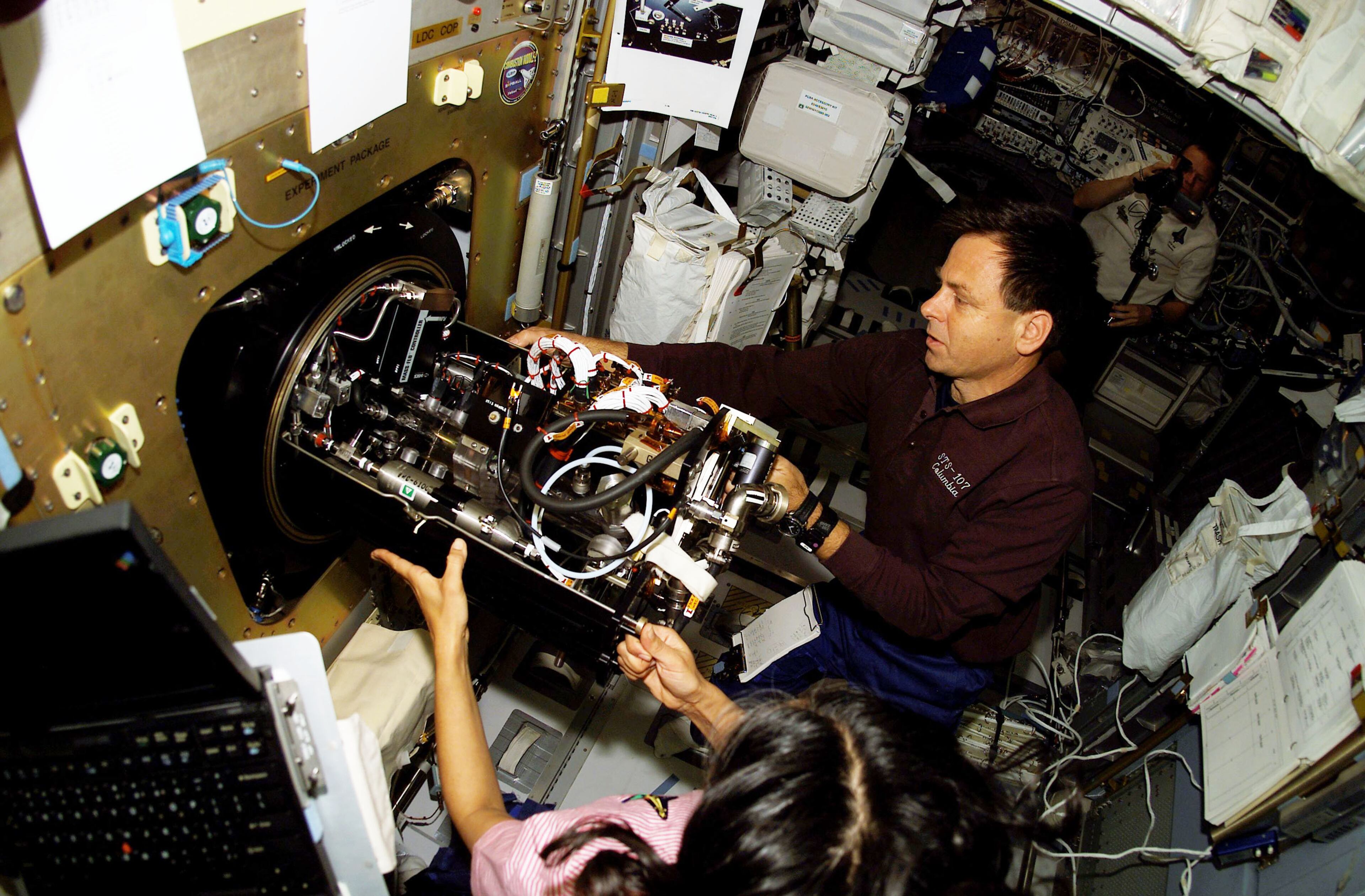 IN SPACE - JANUARY 27: Ilan Ramon (C), STS-107 payload specialist, and astronaut Kalpana Chawla (L), mission specialist, work with the Combustion Module-2 facility in the SPACEHAB Research Double Module aboard the Space Shuttle Columbia January 27, 2003 In Space. Ramon represents the Israeli Space Agency. (Photo by NASA/Getty Images)