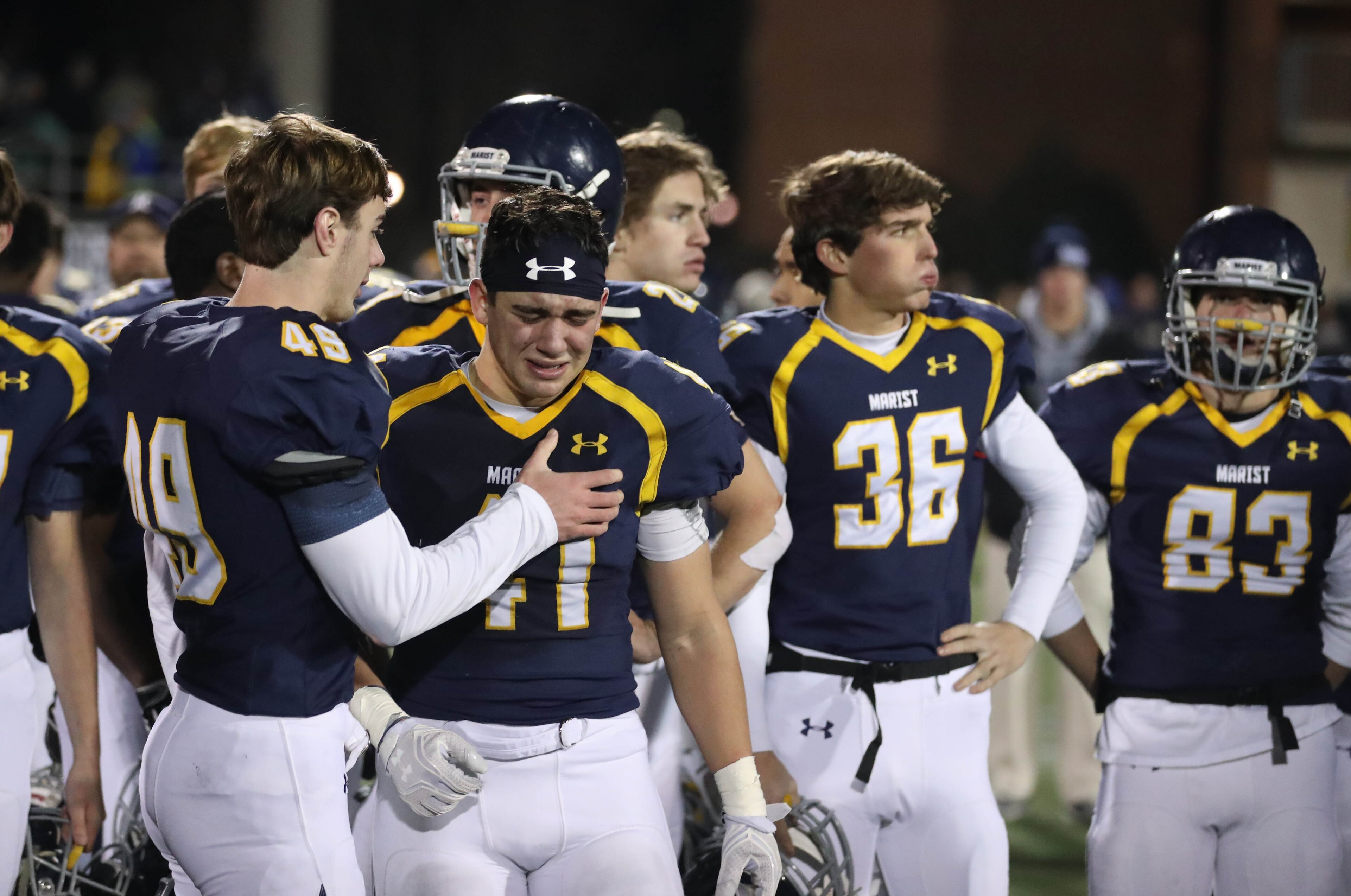 Marist linebacker James Calhoun (49) consoles linebacker Joseph McDermond (41) after their loss to Blessed Trinity in the Class AAAA Championship game at Marist School Friday, December 15, 2017, in Atlanta. Blessed Trinity won 16-7. PHOTO / JASON GETZ