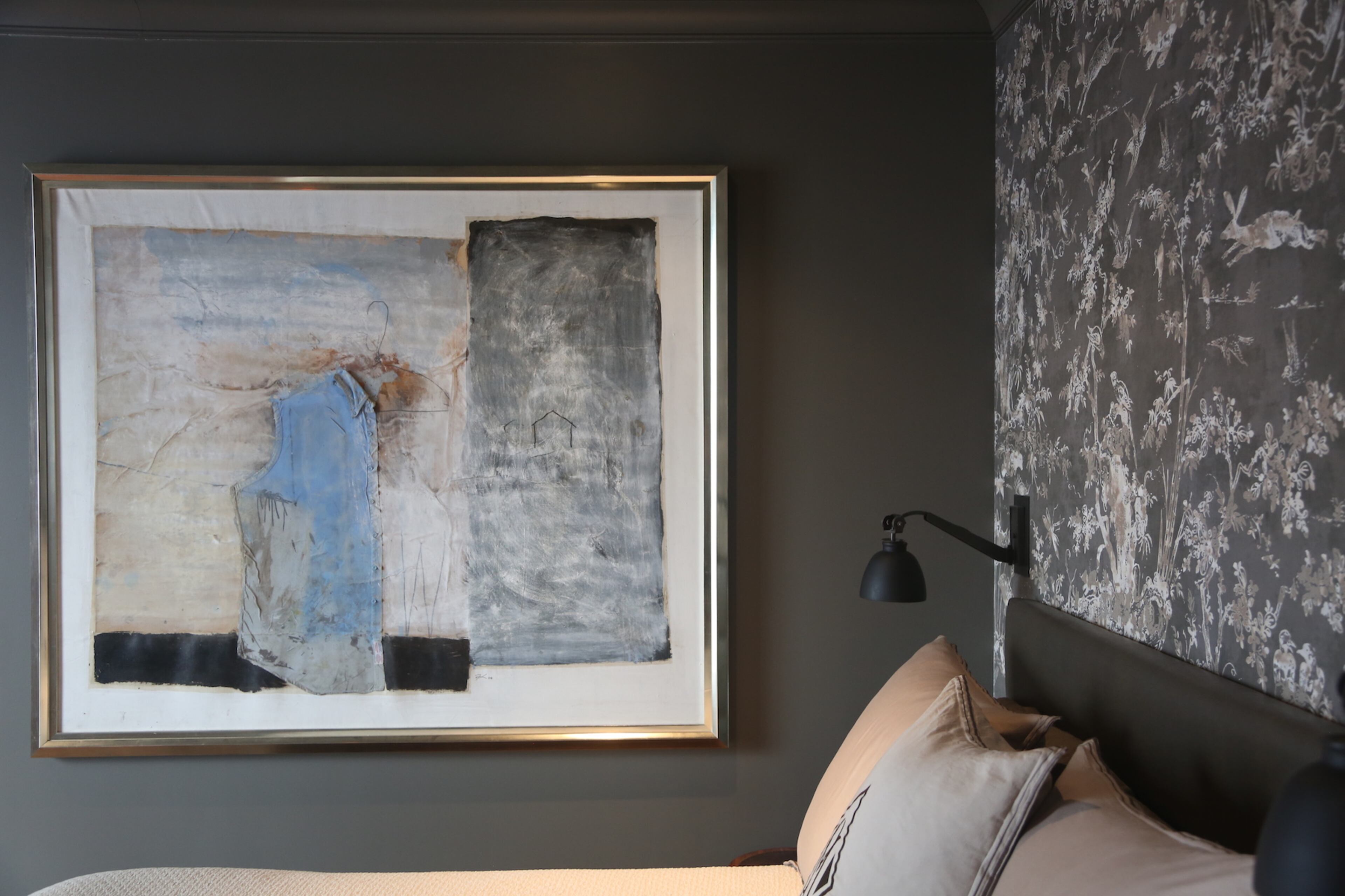 Walls painted Sherwin-Williams' Dovetail are set for original art and designer wallpaper depicting a forest scene.