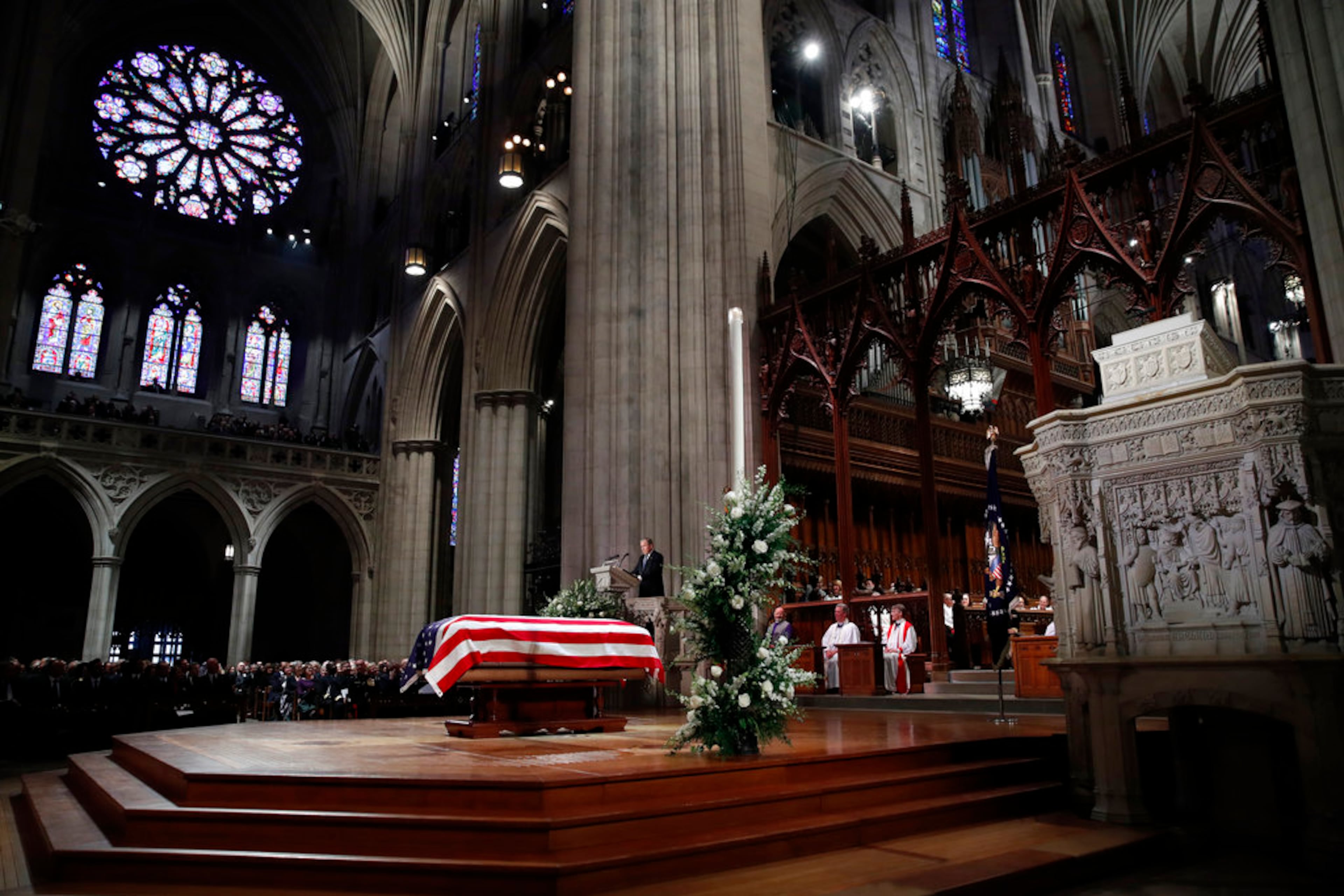 Former President George W. Bush speaks in front of the flag-draped casket of his father, former President George H.W. Bush, at the State Funeral at the National Cathedral, Wednesday, Dec. 5, 2018, in Washington. (AP Photo/Alex Brandon, Pool)