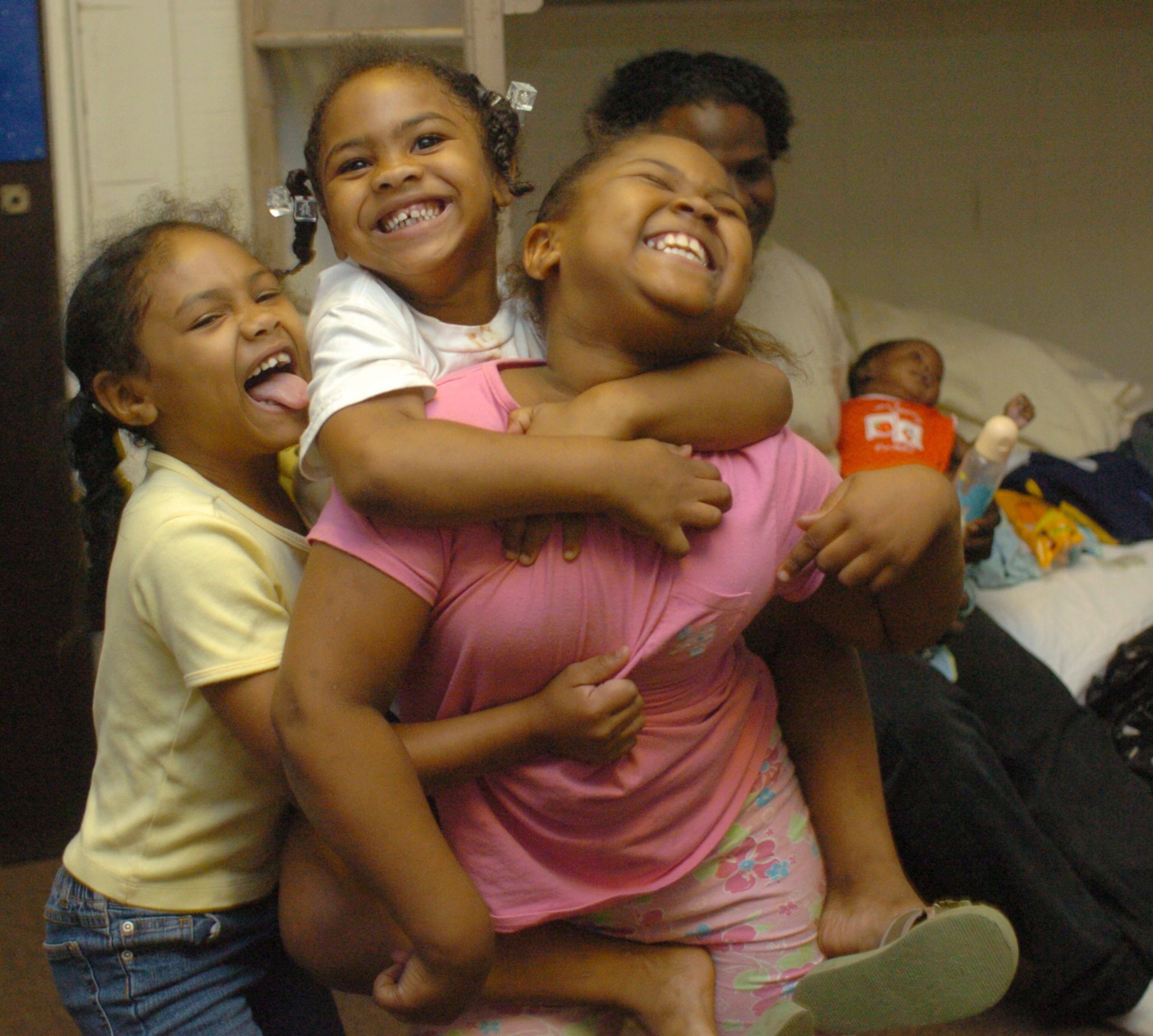 050902 Covington Ga: Starr Esteen (cq) (lft) 4yrs old, Sasia Esteen (cq) (2nd) 5, and Summer Esteen (cq) (rt) 7, are sisters and seem to have no thought of being homeless but just enjoying a new place to play as they settle into a cabin provided by the Future Farmers of America Center. In the background is their uncle Shajuan Esteen (cq) with his daughter Sasha Esteen (cq) (rt/back/baby) 3months old. Sept 2, 2005 (Renee' Hannans Henry/Staff).