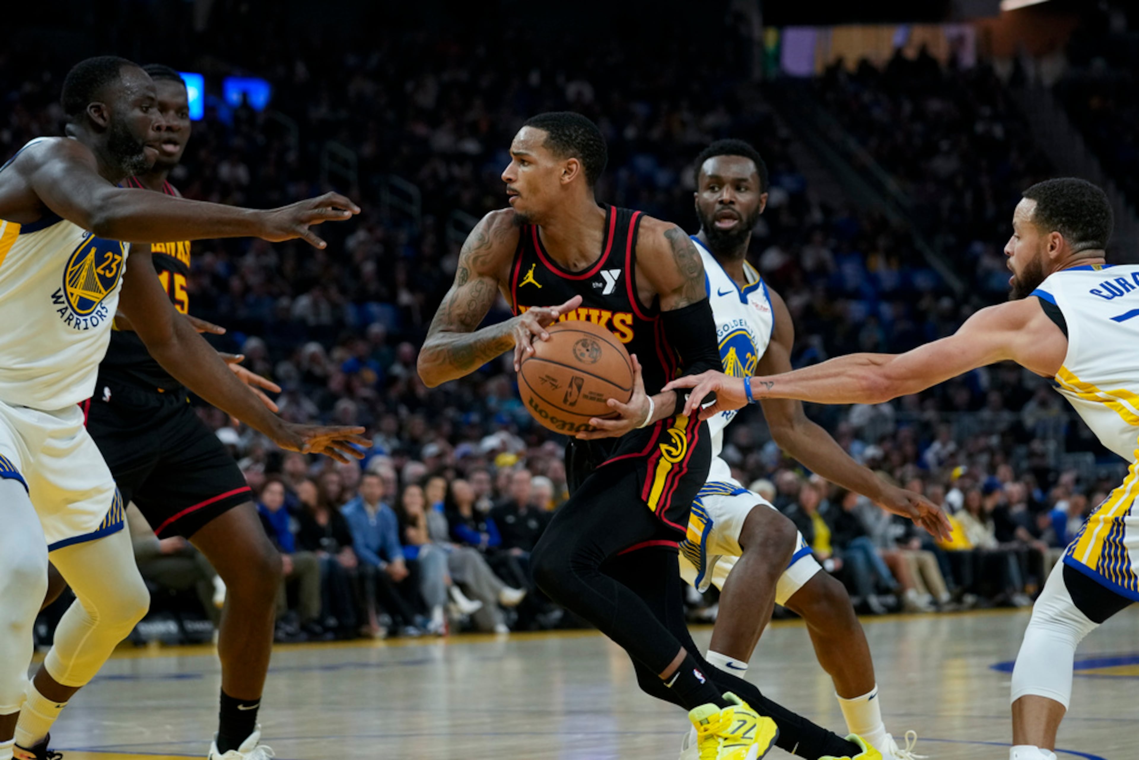 Atlanta Hawks guard Dejounte Murray, center, moves the ball between Golden State Warriors forward Draymond Green, left and guard Stephen Curry during the first half of an NBA basketball game, Wednesday, Jan. 24, 2024, in San Francisco. (AP Photo/Godofredo A. Vásquez)