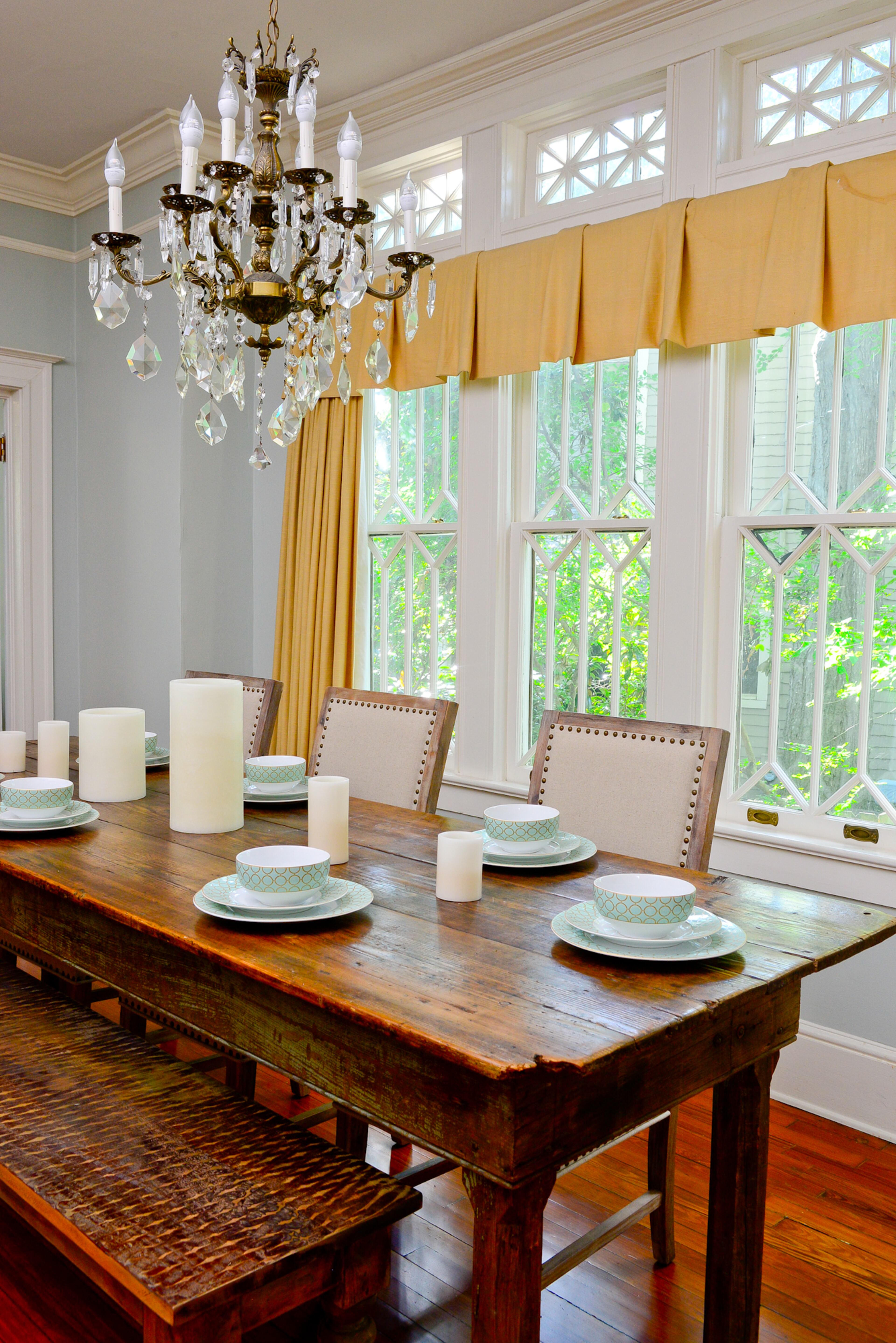 Cromwell Baun and his guests gather around a farm table dating to the late 1800s, from Lakewood 400 Antiques Market, in the dining room. The antique bench is from Rina Norwood Design. Crystals dangling from the chandelier, purchased at Scott Antiques Market and nailhead trim on the chairs add a sense of formality to the space.