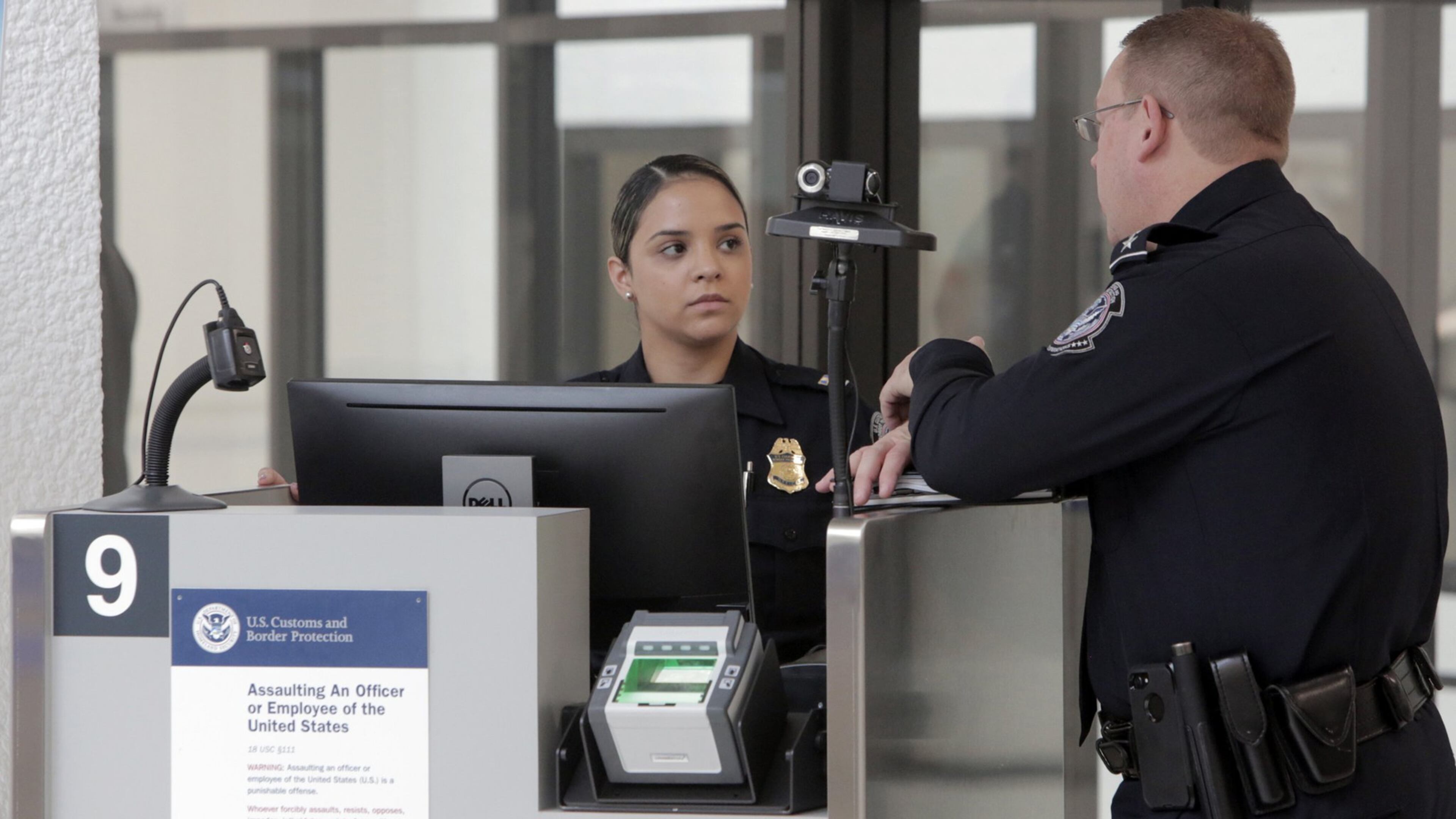 Two agents of U.S. Customs and Border Protection talk on Feb 27, 2018 while waiting for passengers to arrive at one of the facial recognition stations now operating at Miami International Airport. (Jose A. Iglesias/Miami Herald/TNS)