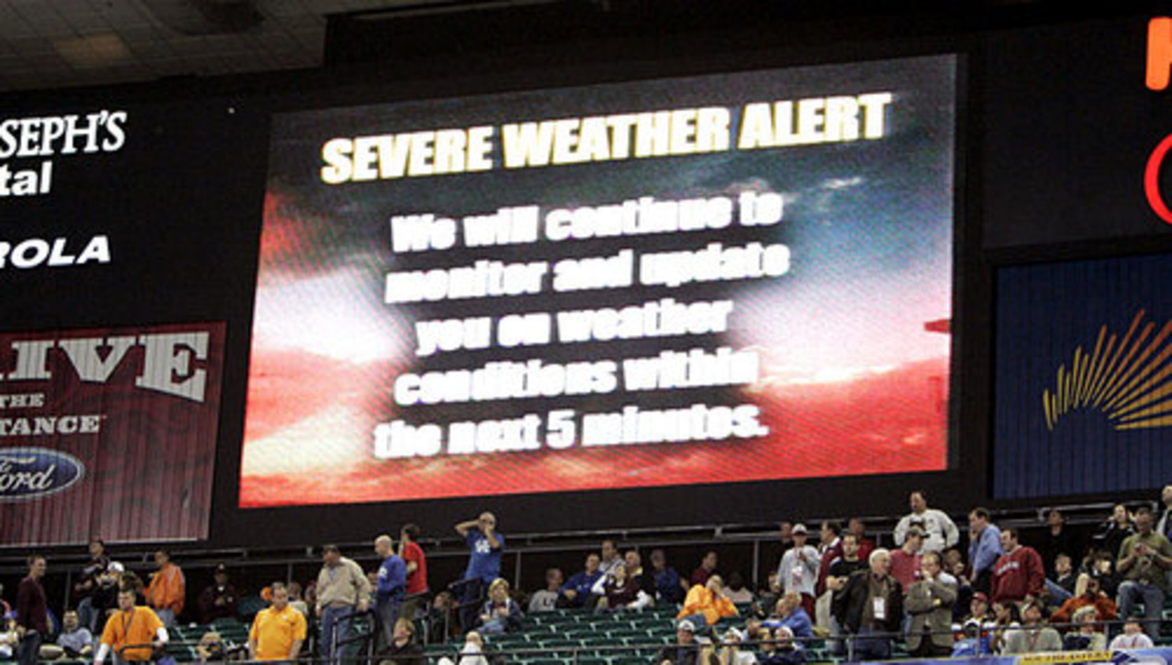 A weather warning is displayed on a television screen hanging near the basketball court in the Georgia Dome after a wind storm halted the Mississippi State-Alabama game during overtime.