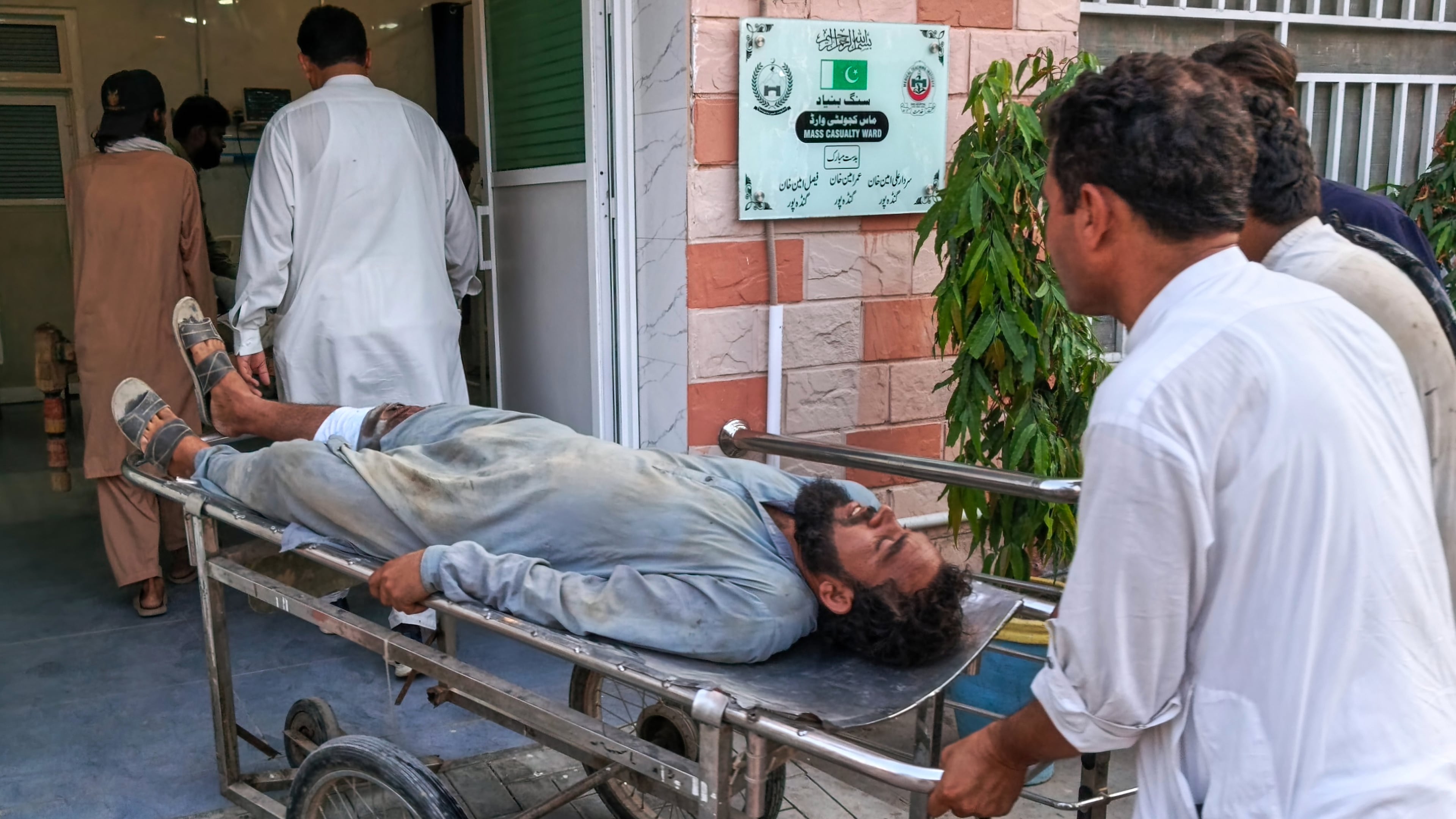 In this photo taken with a smartphone, volunteers transport an injured victim of a suicide attack on a roadside police checkpoint upon his arrival at a hospital in Dera Ismail Khan, Pakistan, Saturday, Sept. 26, 2026. (AP Photo/Kashif Naveed)