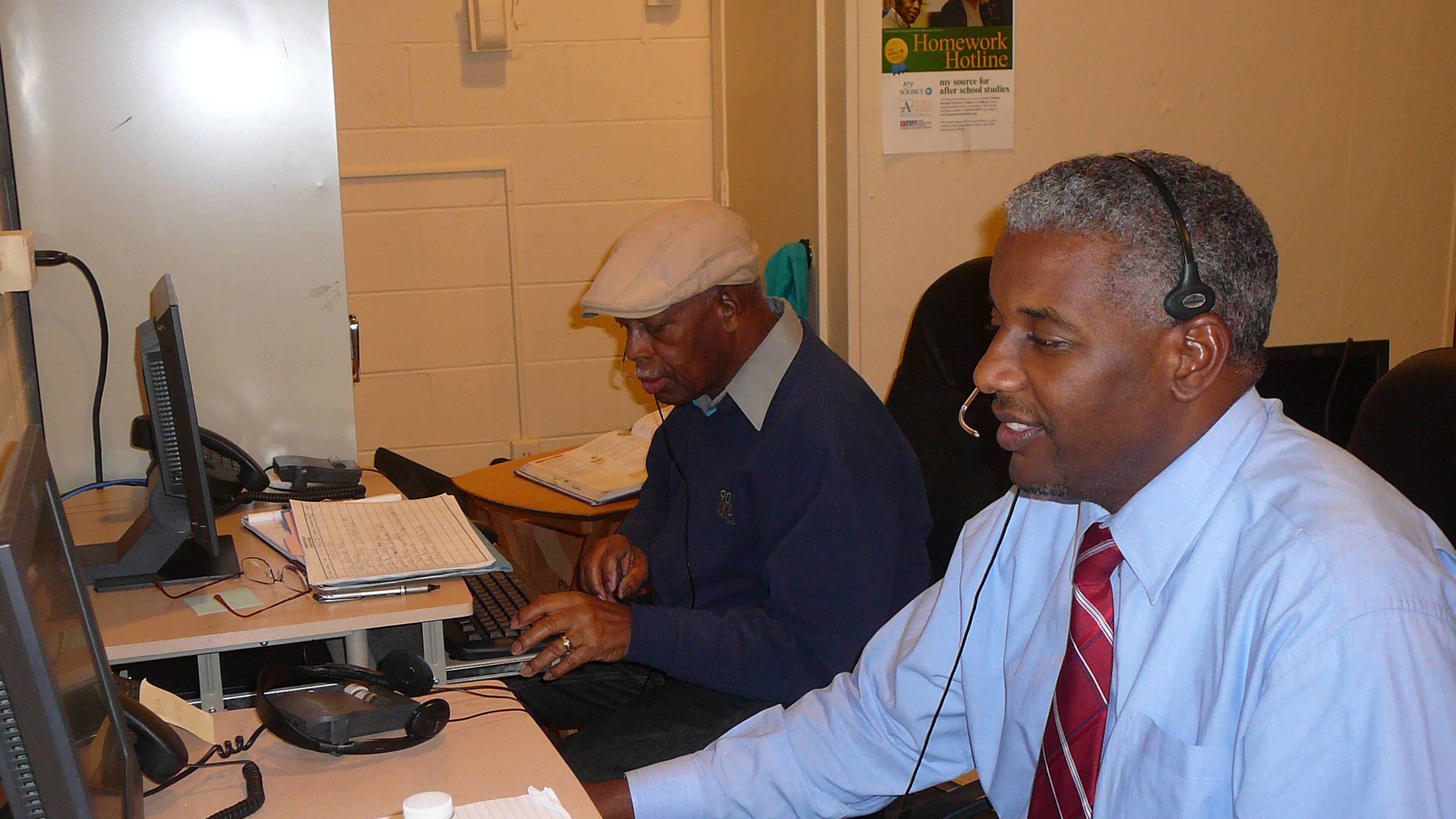 Glenn Randall (l) and Kevin Wright answer calls at the Homework Hotline, a free community service provided by the Atlanta Public School system. The 5-member team fields questions from students around the country.