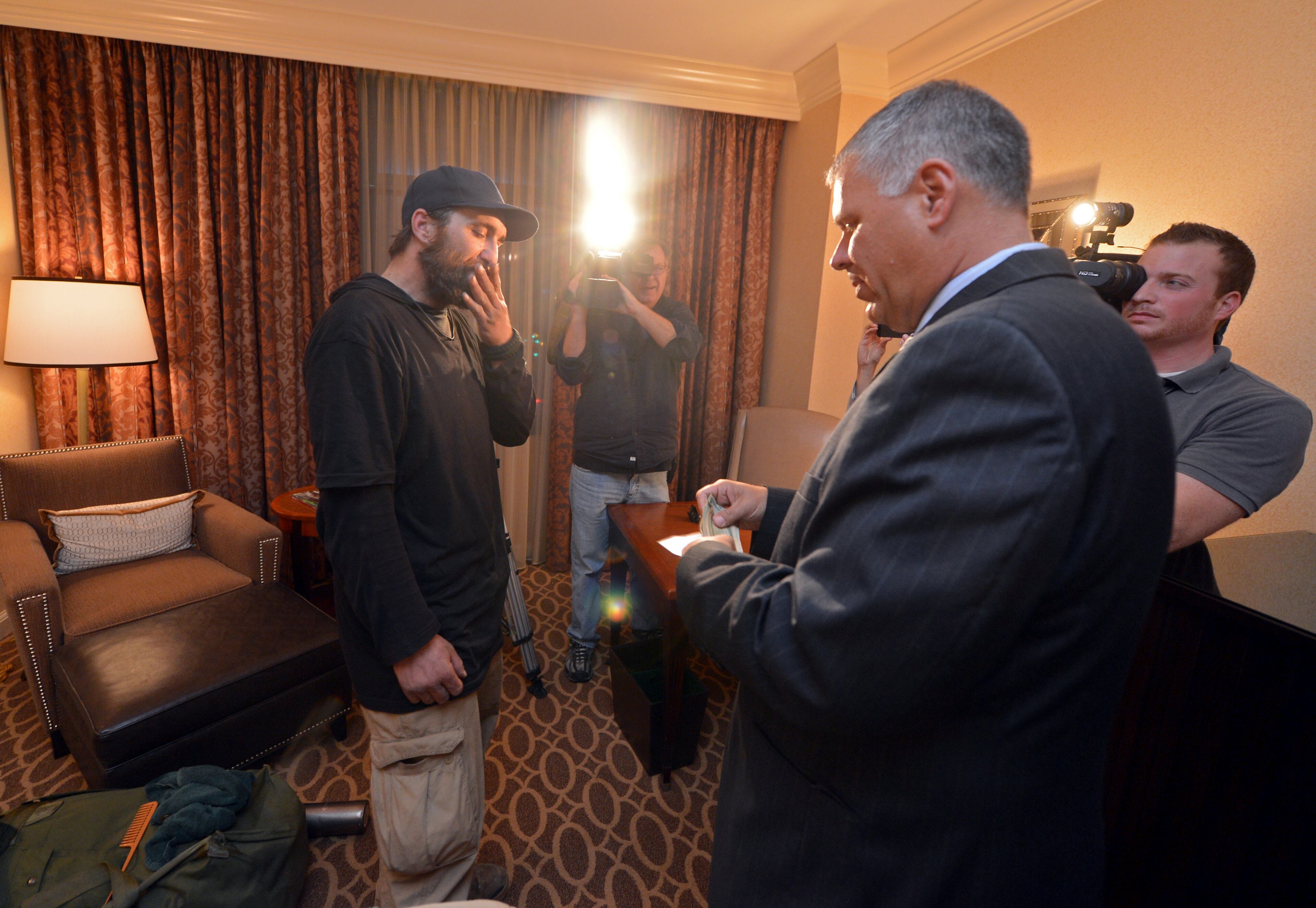 Joel Hartman reacts as Omni Hotel general manager Scott Stuckey gives him $500. Hartman turned in a wallet he found while searching for food in a trash can on November 7, 2013. He went to two hotels until he was able to return the wallet to its owner, a woman staying at the Omni Hotel at CNN Center. Recently hotel officials decided to track down the man and offer him a room, food and money.