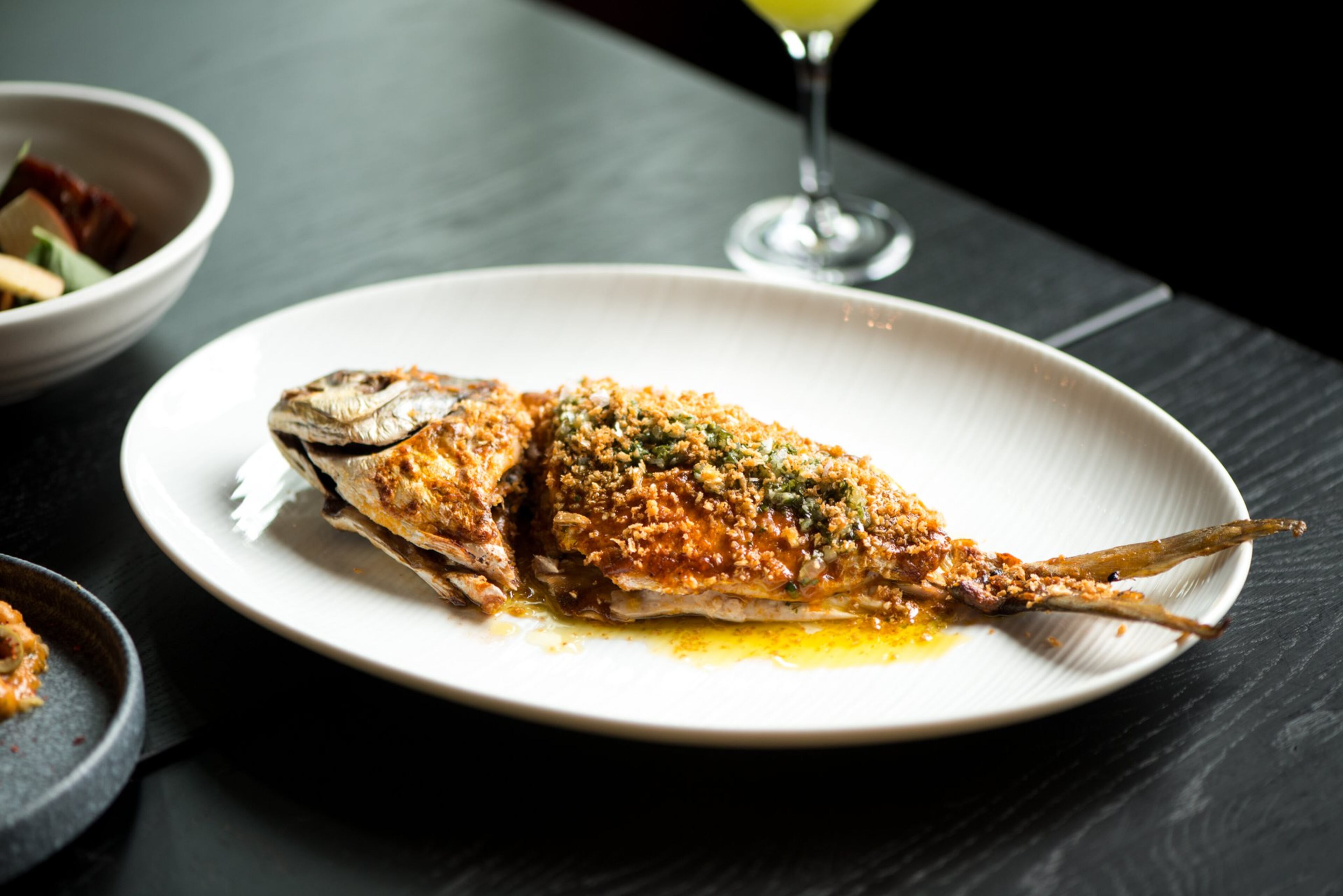 Pescado a la Parilla raciones, whole grilled market fish, grapefruit mojo rojo, and fried garlic. Photo credit- Mia Yakel.