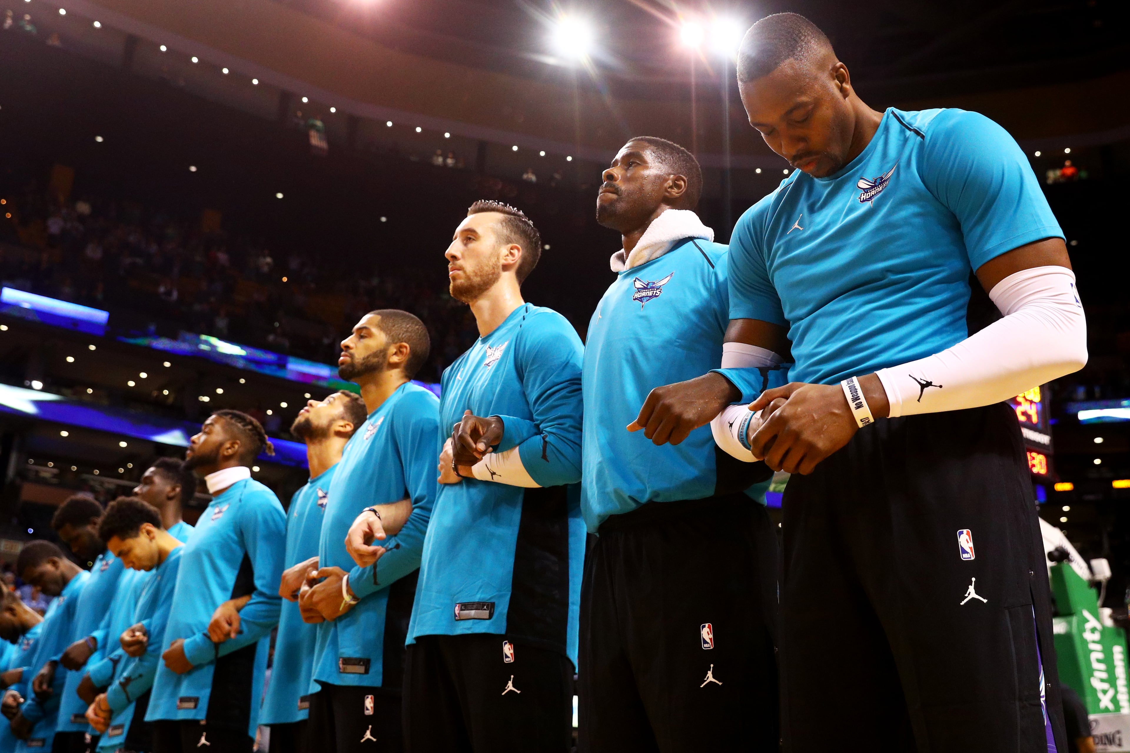 Dwight Howard #12 of the Charlotte Hornets, right, links arms with teammates during the national anthem before the game against the Boston Celtics at TD Garden on October 2, 2017.