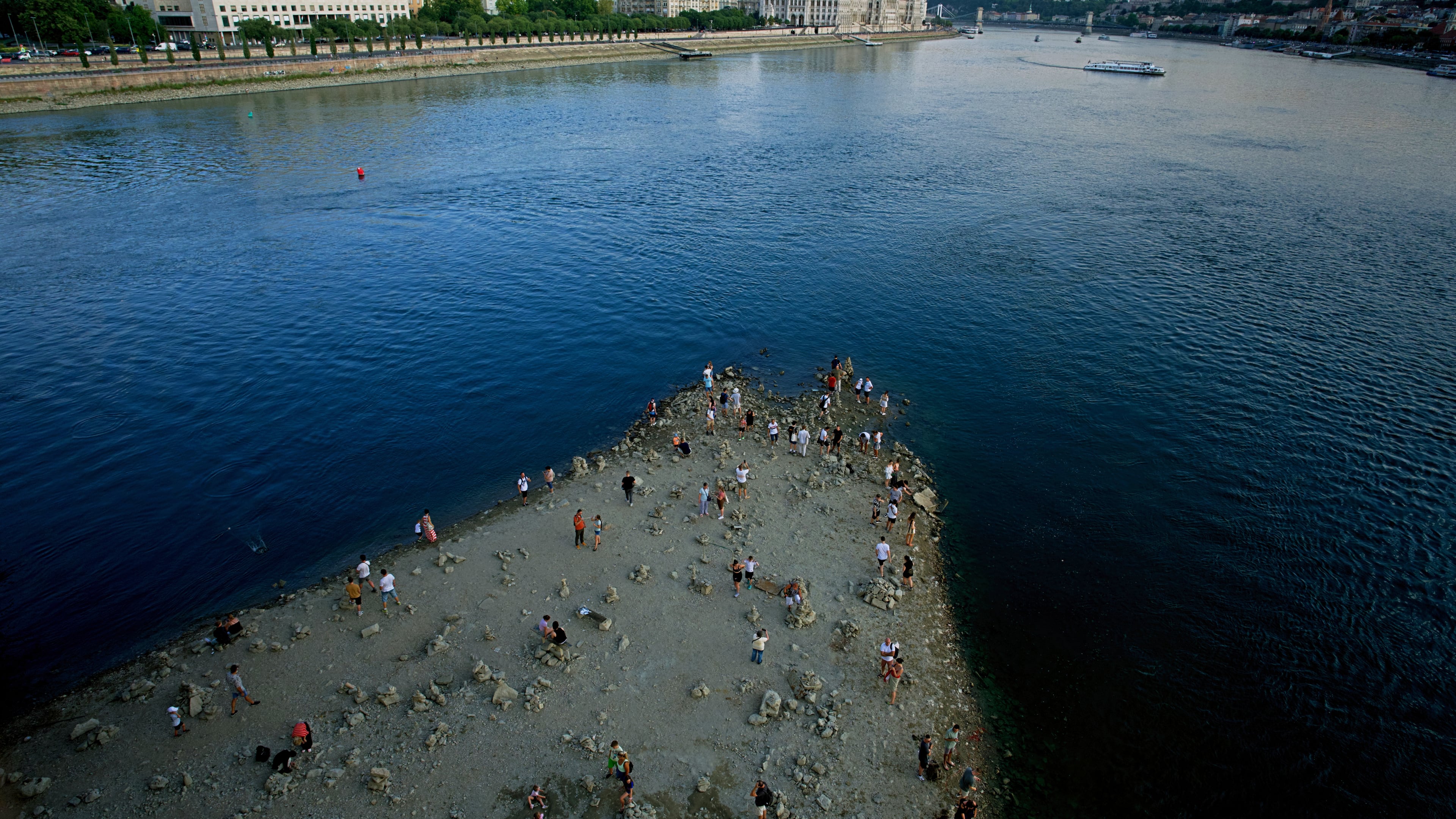People walk on a sandbar underneath the Danube's Margareth Bridge in downtown Budapest, Hungary, Wednesday Aug. 5, 2026, as the river, which runs through 10 European countries, has receded never-before-seen low water levels. (AP Photo/Bela Szandelszky)