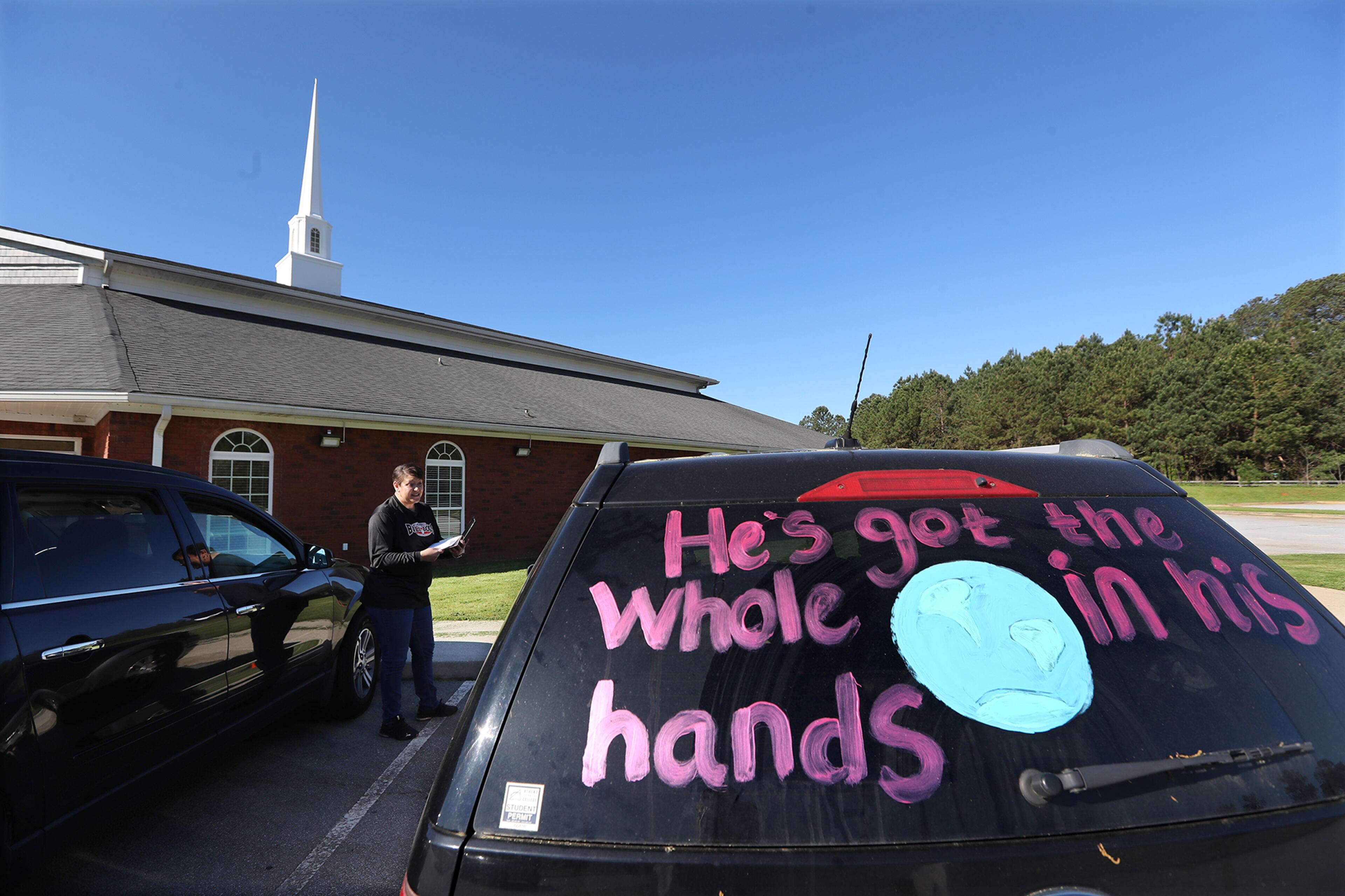 April 2, 2020 Rutledge: Dr. Allison Woodard, Morgan County Middle School, stands in the parking lot providing pass codes to parents and students in their cars looking for Wifi access to complete homework at Union Springs Baptist Church on Thursday, April 2, 2020, in Rutledge. The biggest obstacle to distance learning is finding Wifi. Morgan County has a low-income student population and not every home has internet access. So the school district asked the local church to be a hot spot. Curtis Compton ccompton@ajc.com