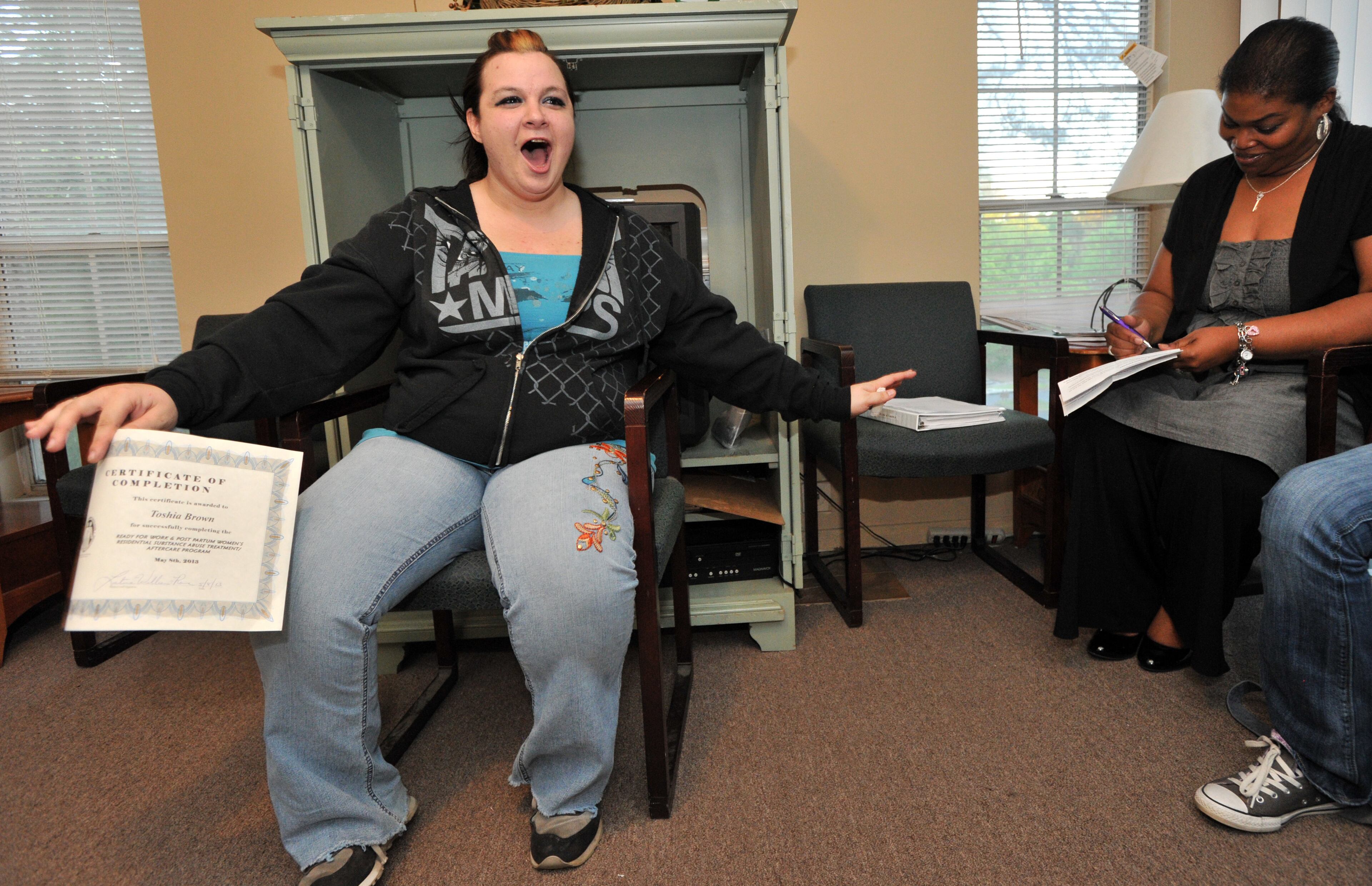 Toshia Brown can't hide her joy as she holds her Certification of Completion as Christy Tennison-Kee (right), Substance Abuse Clinician, looks after Toshia shared her story with other program participants and their family members and friends as a part of the last session of the program during their Family Education Group Night event at a residential facility in Marietta. Today Toshia completed her last session of "Ready for Work and Post Partum Women's Residential Substance Abuse Treatment/Aftercare Program." HYOSUB SHIN / HSHIN@AJC.COM