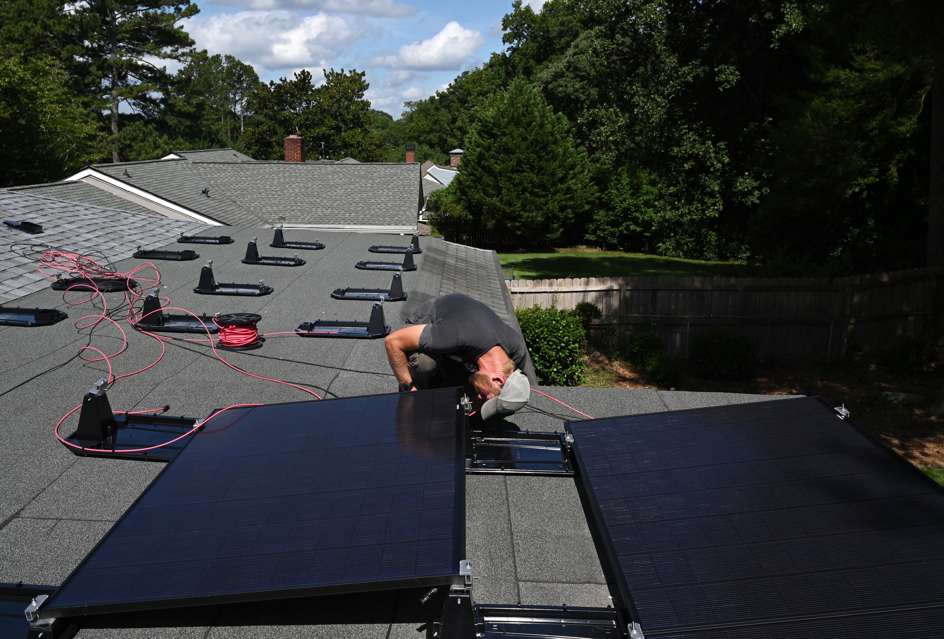 Ryan Johnson with Custom Solar Solutions installs solar panels on the roof of a home, Thursday, July 17, 2025, in North Druid Hills. Companies like Custom Solar Solutions, who have already been impacted by tariff-driven cost increases, expect to be hit even harder by the reconciliation bill which eliminates a crucial tax incentive.(Hyosub Shin/AJC)
