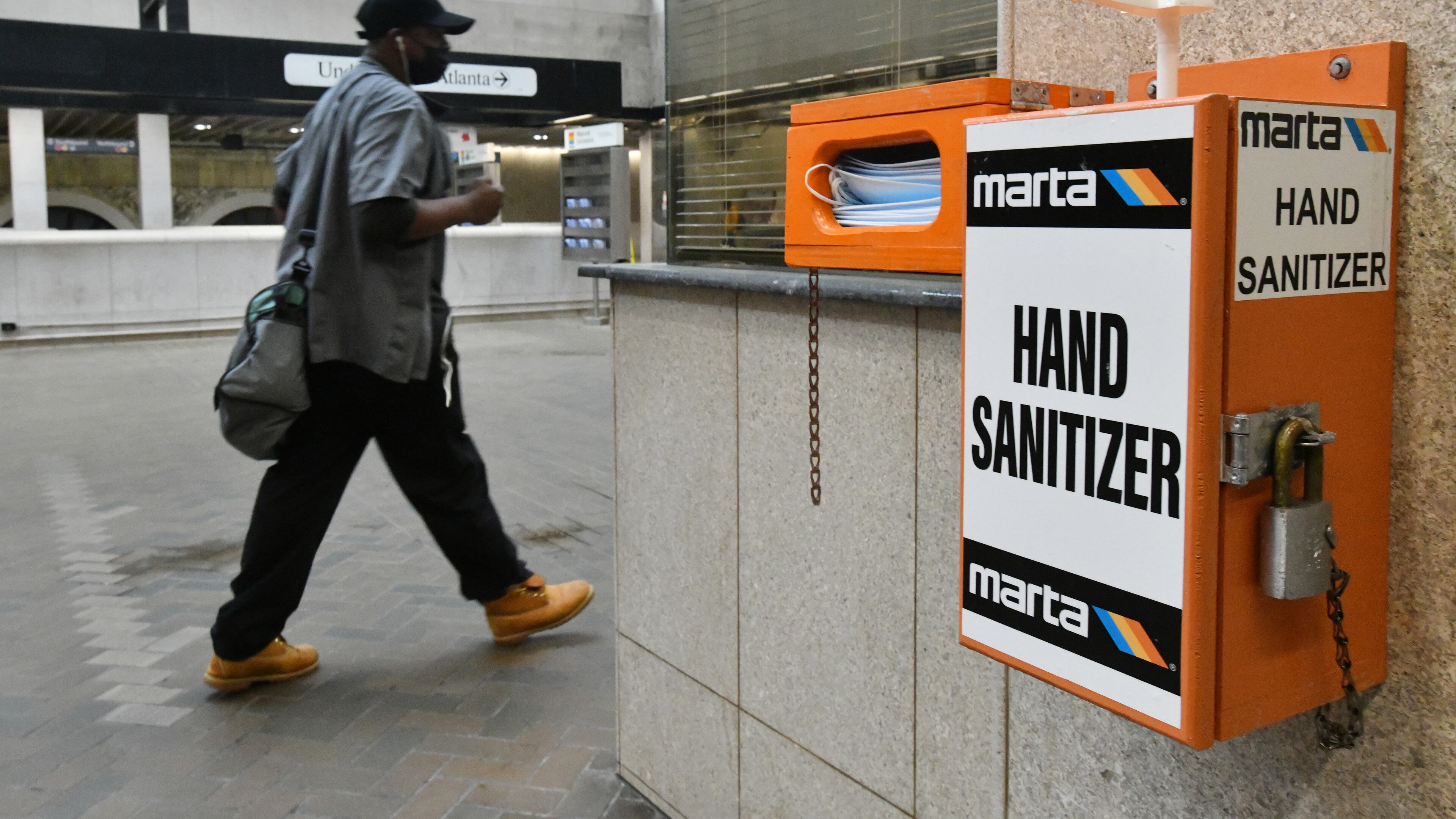 March 25, 2021 Atlanta - A Marta customer walks past mask and hand sanitizer dispensers at the Five Points MARTA station on Thursday, March 25, 2021. MARTA stepped up cleaning of buses and other facilities during the COVID-19 pandemic. It also stopped collecting bus fares for months to limit contact between passengers and drivers, and it saw sales taxes — another key source of revenue — fall. But federal coronavirus recovery aid has helped shore up operations at MARTA and other transit agencies in the region. (Hyosub Shin / Hyosub.Shin@ajc.com)