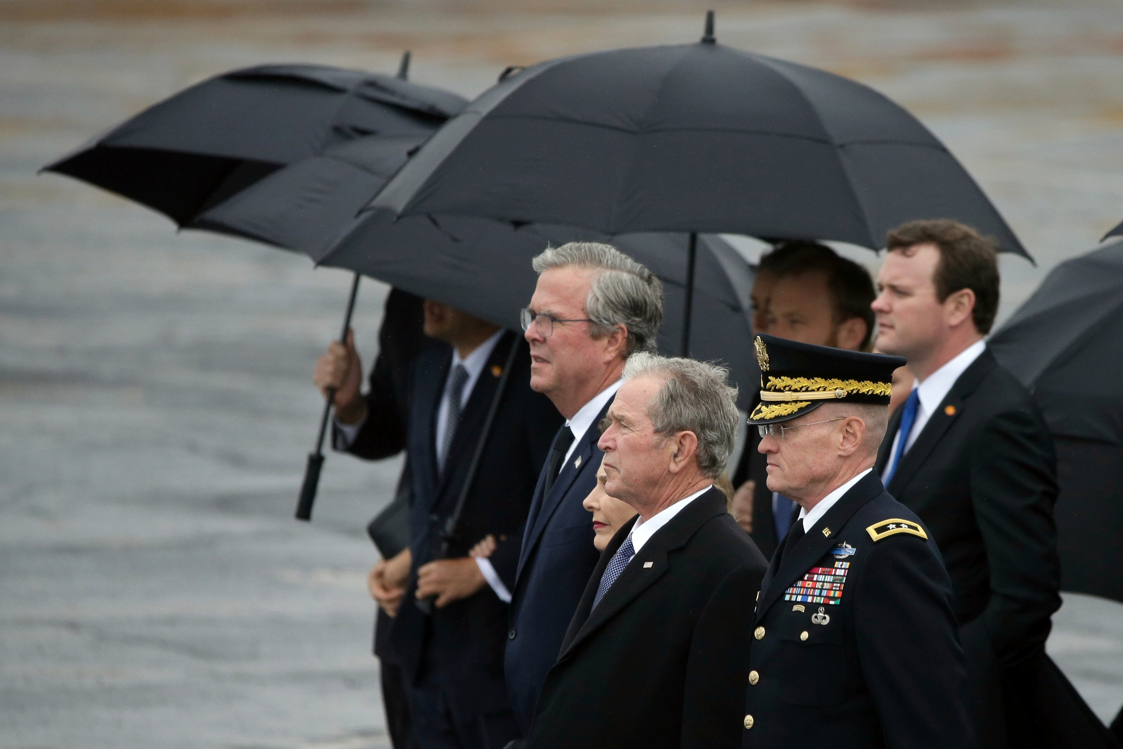 Former President George W. Bush watches as the flag-draped casket of former President George H.W. Bush is carried by a joint services military honor guard to a train at Union Pacific Westfield auto facility Thursday, Dec. 6, 2018, in Spring, Texas. (AP Photo/Kiichiro Sato)