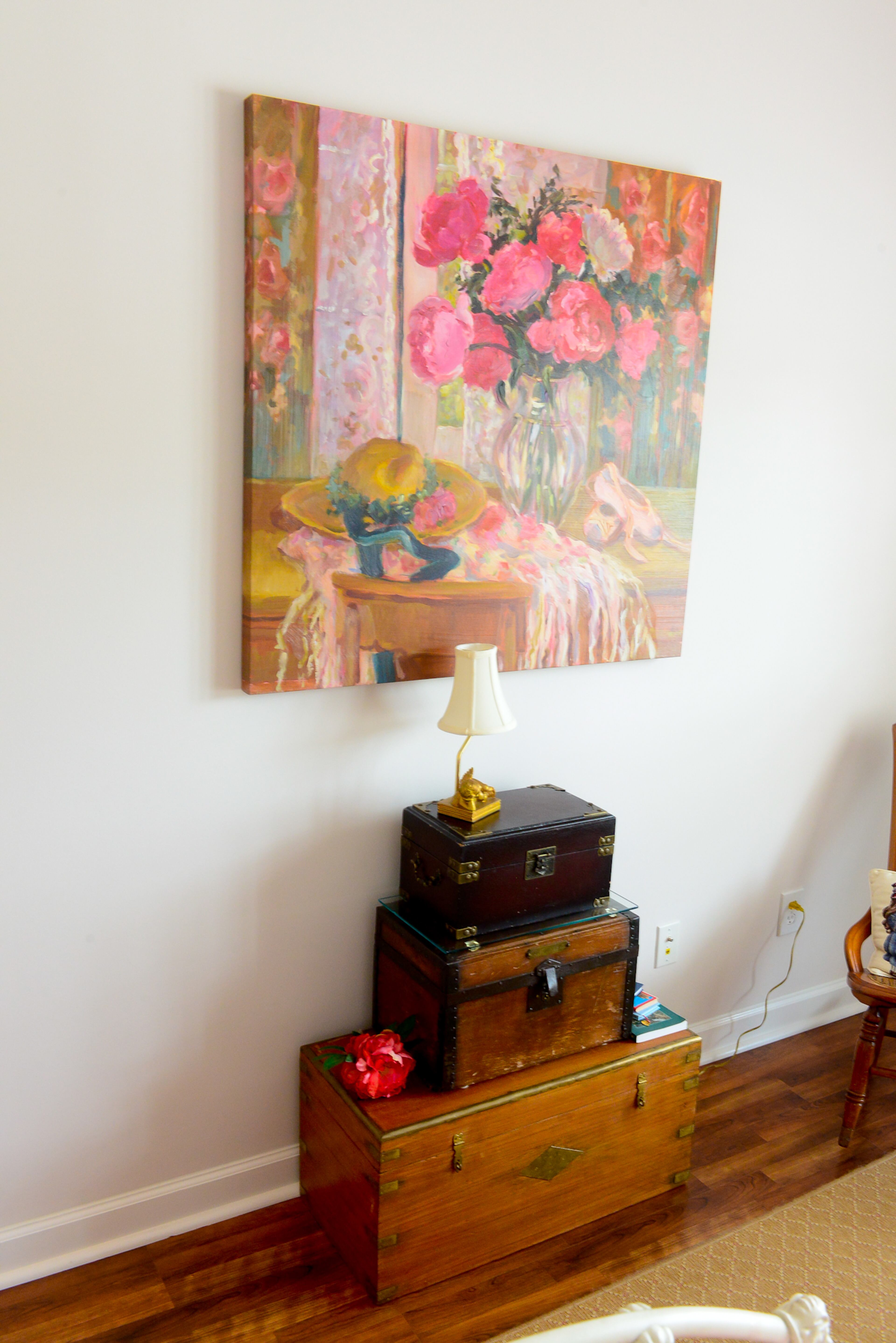 The colors in this piece of art inspired Linda to decorate her guest bedroom in a palette her three granddaughters could appreciate into their teens. The pinks and reds in the artwork's slippers and florals coordinate with the pink coverlets and other accessories in the room. Stacked trunks topped with a lamp give the room a bit of vintage sophistication.