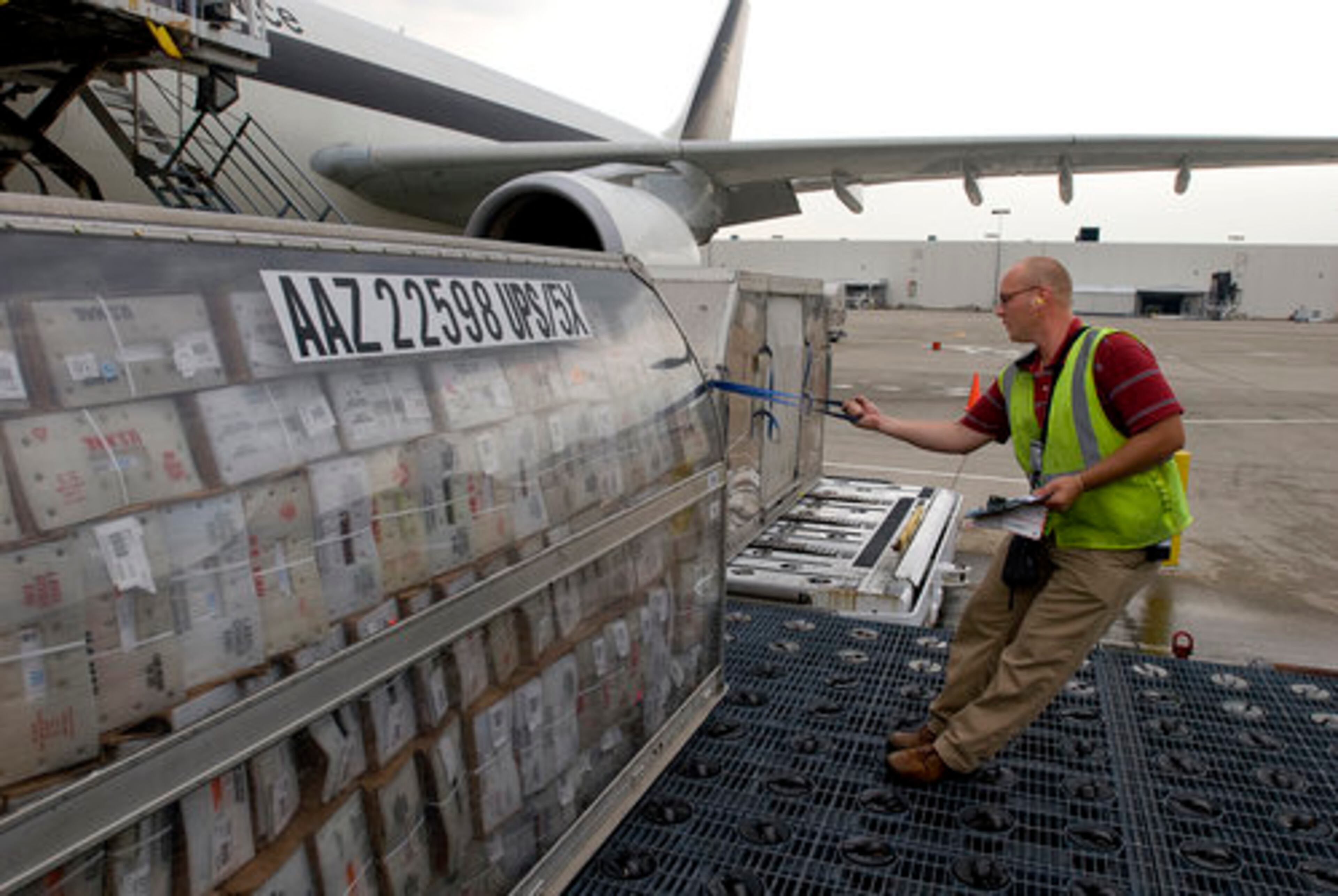 Biller pulls a "can" full of packages from a plane so it can be loaded onto a dolly and moved.