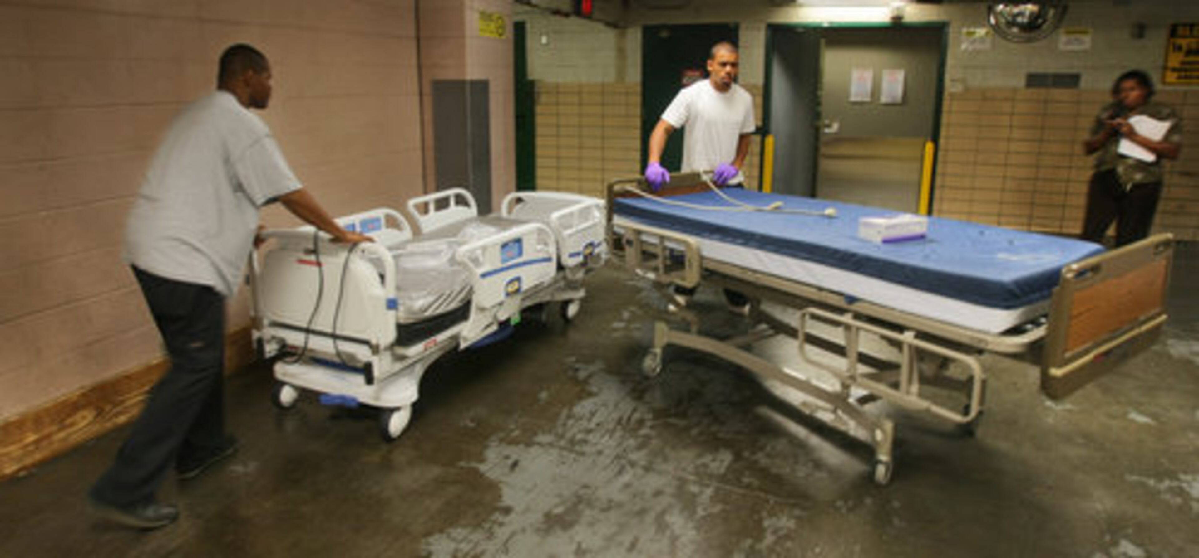 Grady Memorial Hospital is getting 604 new high-tech beds to replace all its old, dilapidated ones. Fritz Braves (left) rolls up a new bed as Nathaniel Banks rolls out the old.