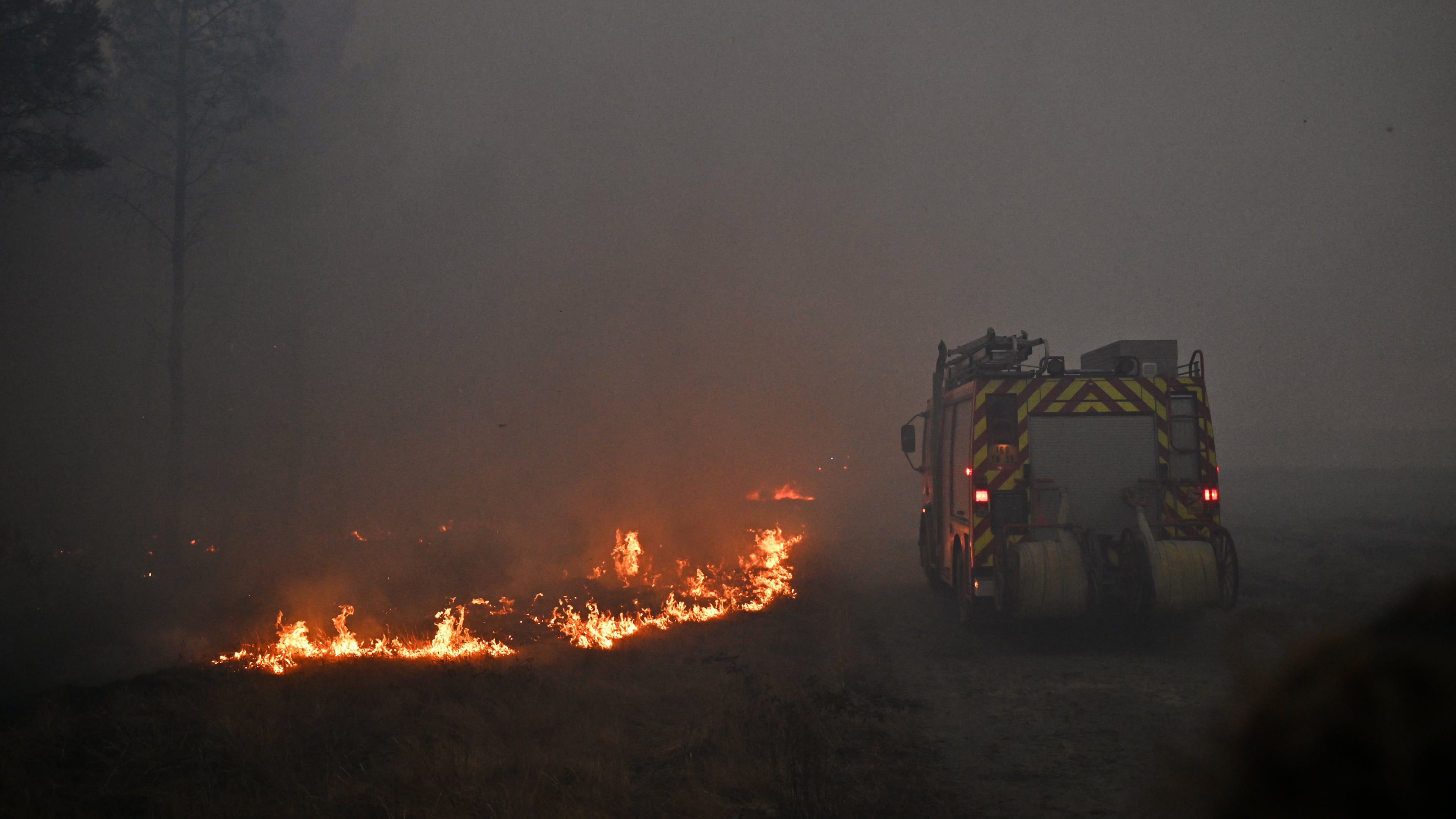 A fire engine drives through smoke of a wildfire raging near Marcheprime, outside, Bordeaux, France, Sunday, July 26, 2026. (AP Photo/Emma Da Silva)