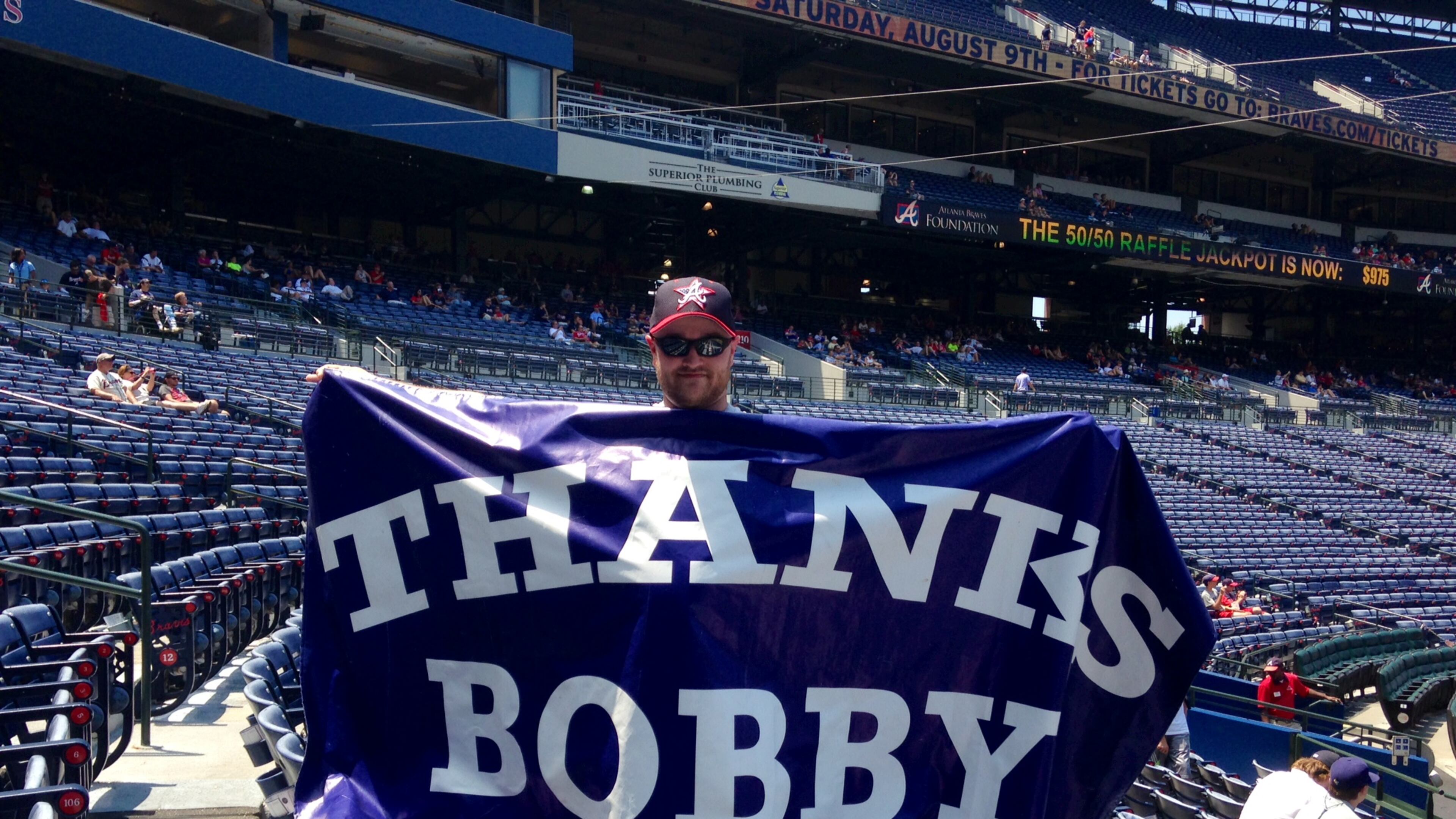 Jason O’Neal holds a “Thanks Bobby” sign up from the stands at Turner Field during Sunday’s Hall of Fame induction screening.
