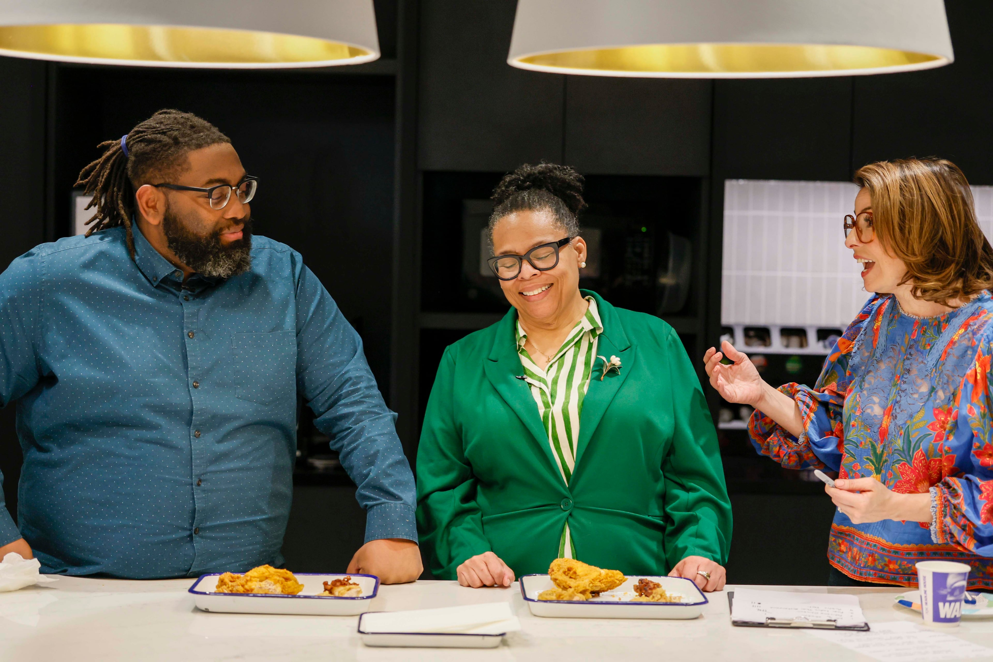 AJC Food & Dining Senior Editor Monti Carlo discusses with Social Media Manager Anderson Serrant and Director of Visual Content Sandra Brown the flavors of various fried chicken pieces during a fried chicken contest on Tuesday, Aug. 25, 2026, at the AJC office in Midtown. The event aims to determine Atlanta’s best fried chicken. (Miguel Martinez/AJC)