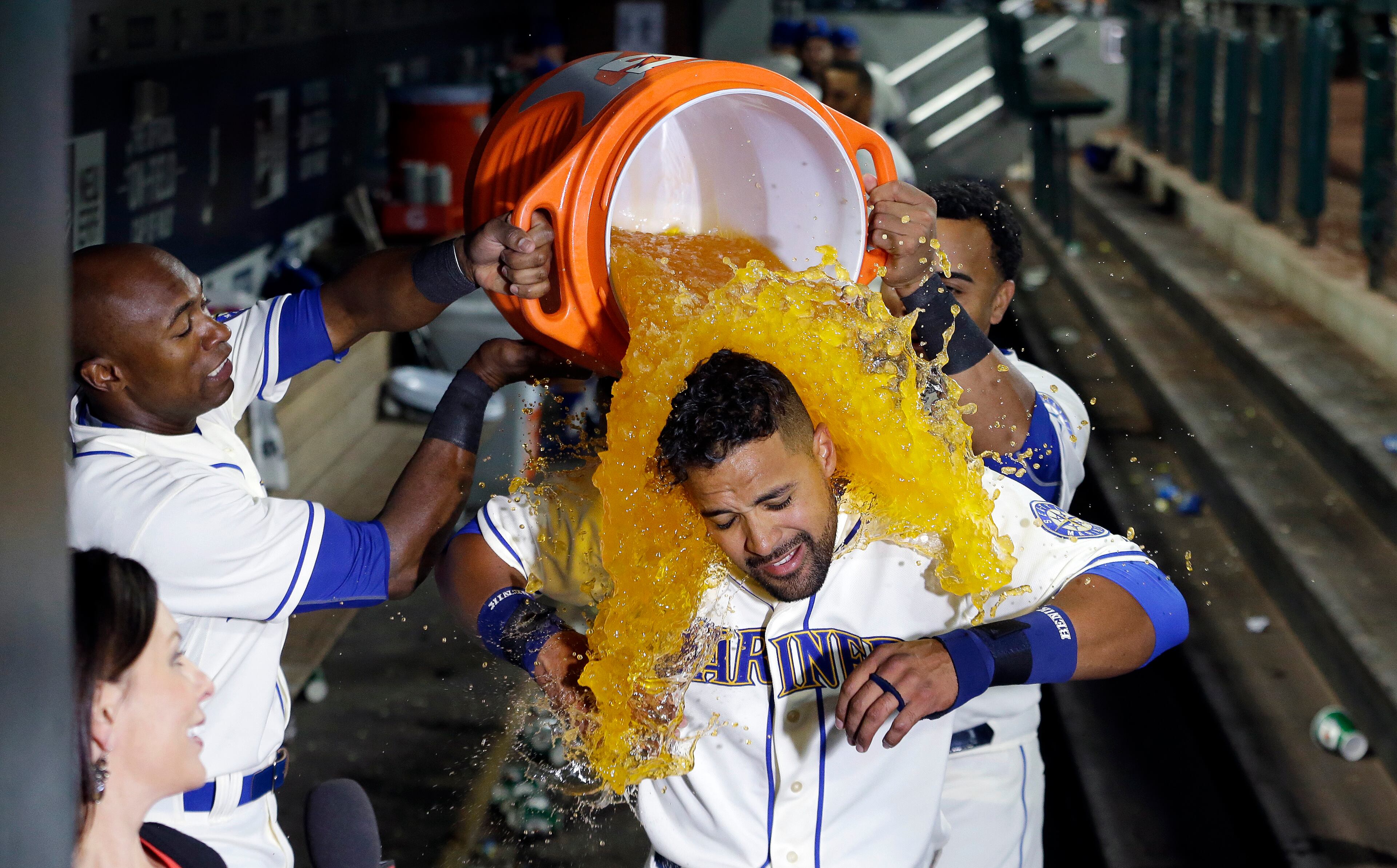 Seattle Mariners' Franklin Gutierrez, center, is doused with a bucket of a sports drink by teammates Austin Jackson, left, and Nelson Cruz after Gutierrez's home run that beat the Toronto Blue Jays in the 10th inning of a baseball game Sunday, July 26, 2015, in Seattle. The Mariners won 6-5. (AP Photo/Elaine Thompson)
