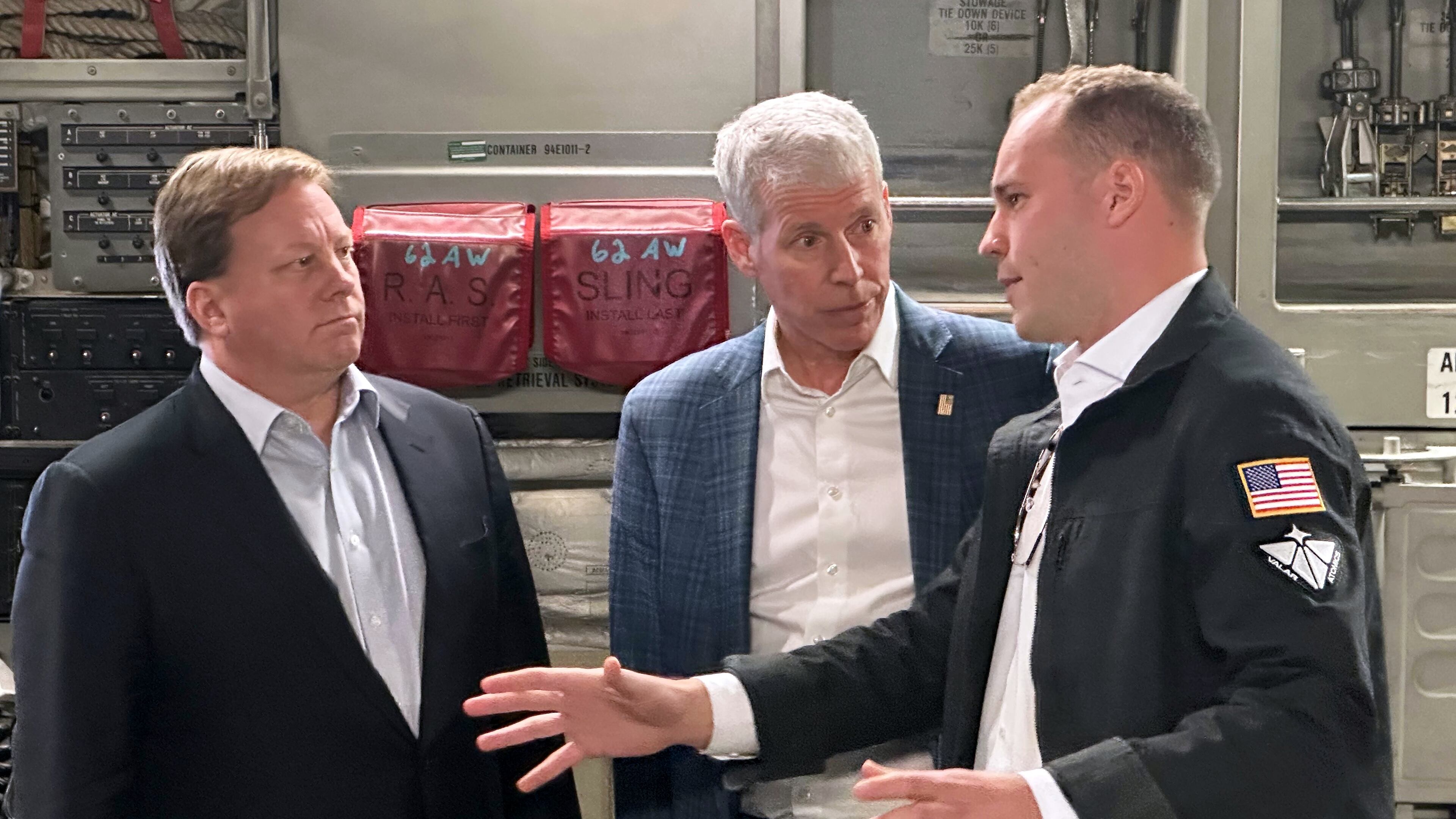 Energy Secretary Chris Wright, center, and Under Secretary of Defense Michael Duffey, left, listen as Isaiah Taylor, CEO of Valar Atomics, discusses a microreactor developed by Valar to generate nuclear power for the military and commercial customers, Sunday, Feb. 15, 2026, in-flight, on board a C-17. (AP Photo/Matthew Daly)