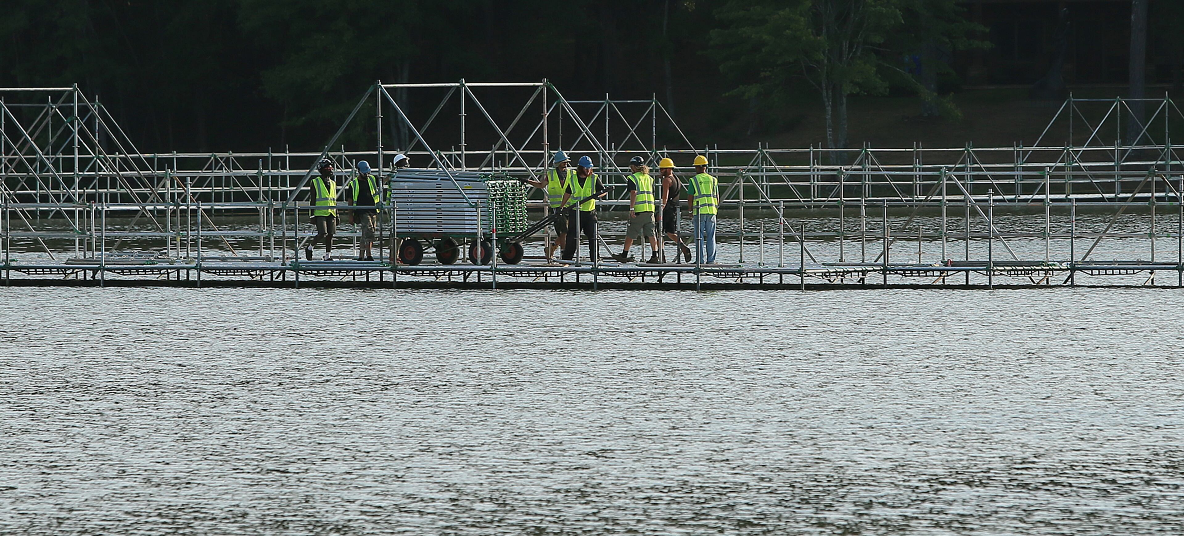 Construction workers build a pedestrian walkway across the top of a lake at the TomorrowWorld Festival site on Wednesday, Sept. 18, 2013, in Fairburn.