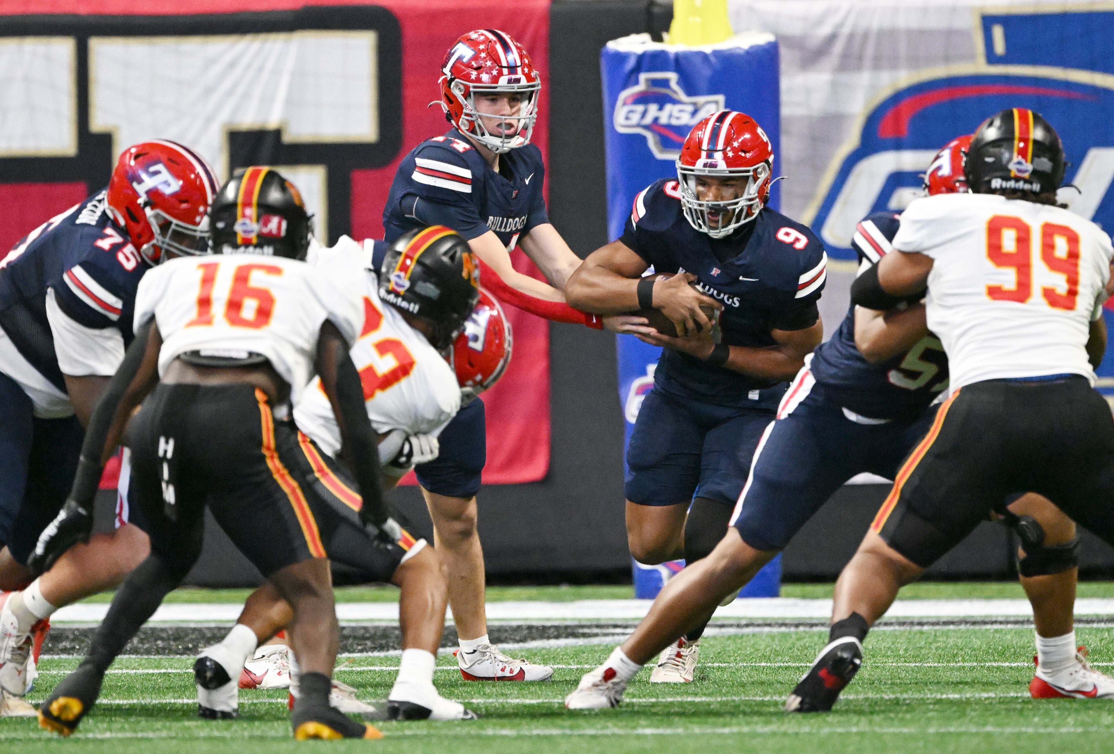 Toombs County's quarterback Tj Stanley (14) makes a handoff to Toombs County's running back Justin Powell (9) during the first half in GHSA Class A-Division State Championship game at Mercedes-Benz Stadium, Tuesday, December 17, 2024, in Atlanta. (Hyosub Shin / AJC)