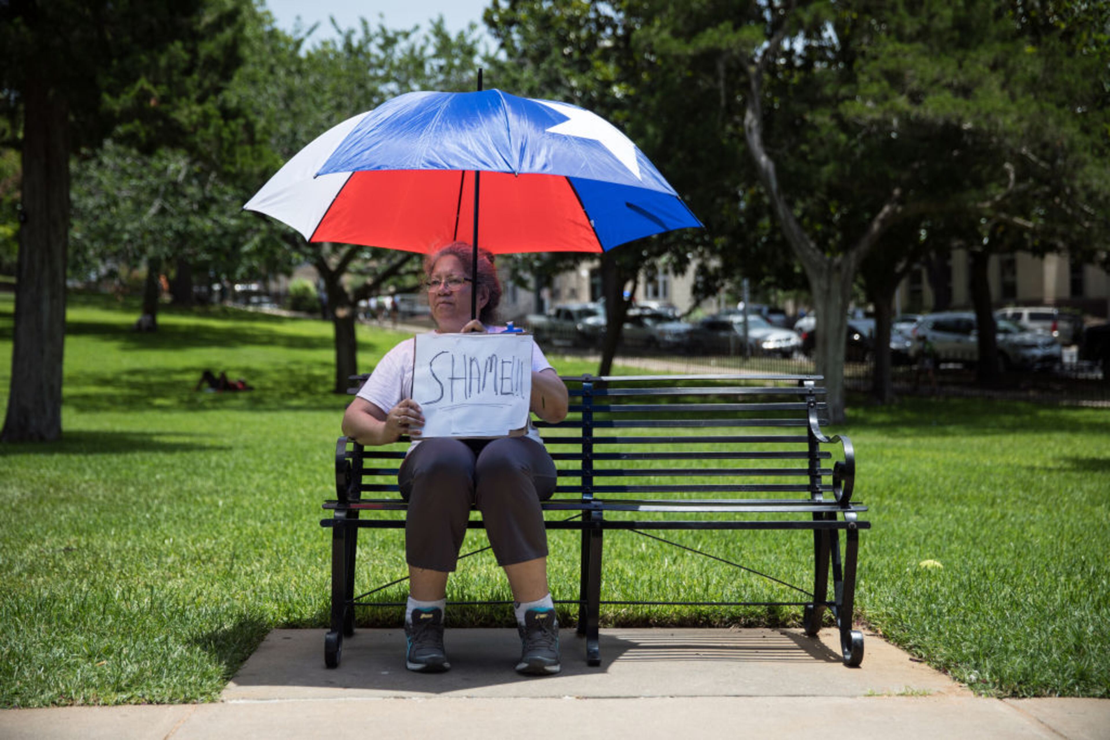 AUSTIN, TX - JUNE 30: Henrietta Cameron-Mann holds a protest sign while sitting under an umbrella inspired by the Texas flag during rally against the Trump administration's immigration policies outside of the Texas Capitol in Austin, Texas, on June 30, 2018. Demonstrations are being held in cities across the U.S. Saturday to call for the reunification of separated families and to protest the detention of children and families seeking asylum at the border. (Photo by Tamir Kalifa/Getty Images)