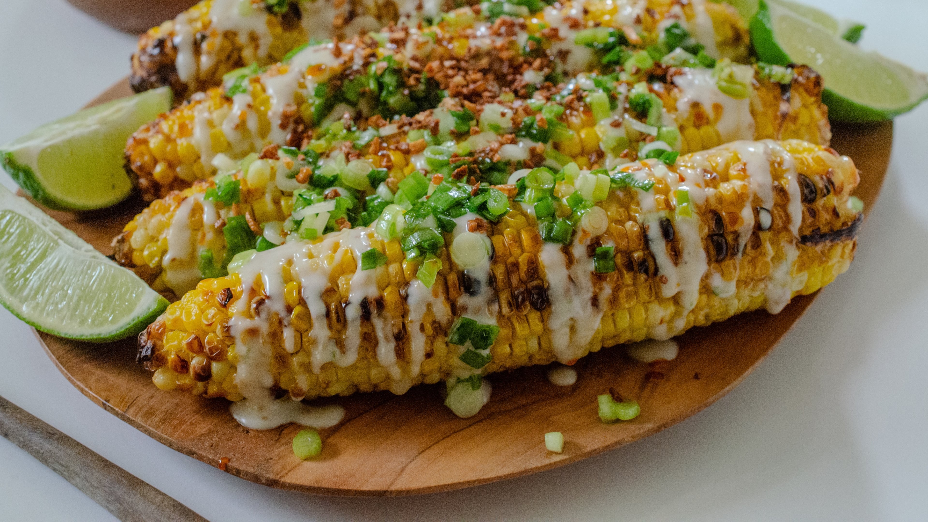 Corn on the cob topped with a coconut milk reduction, scallions, garlic and hot chile oil make a flavorful fusion. (Virginia Willis for AJC)