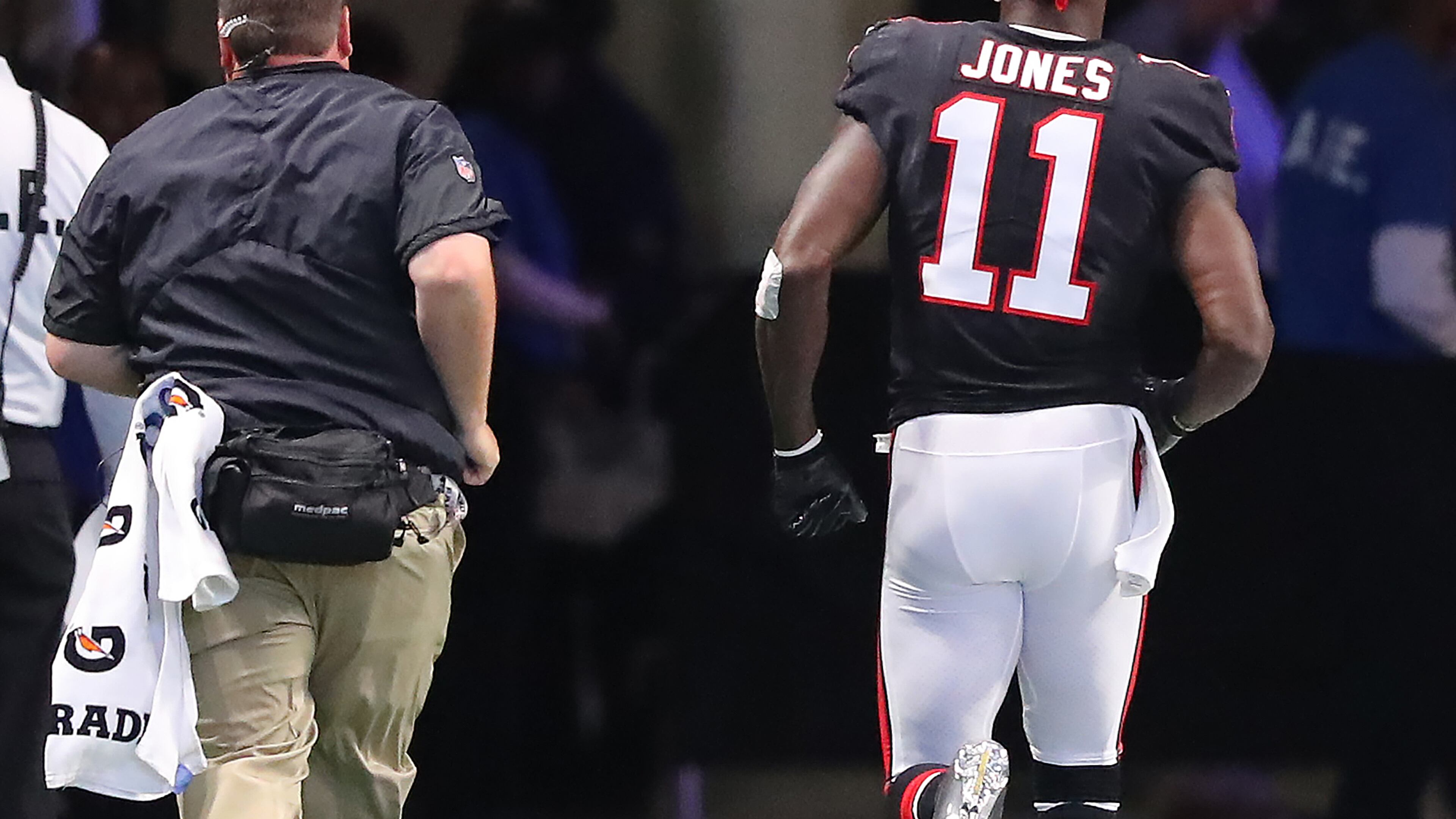 Never a good sign: Falcons wide receiver Julio Jones leaves the field in the first half Sunday for an injury inspection. He didn't return to the game. (Curtis Compton/ccompton@ajc.com)