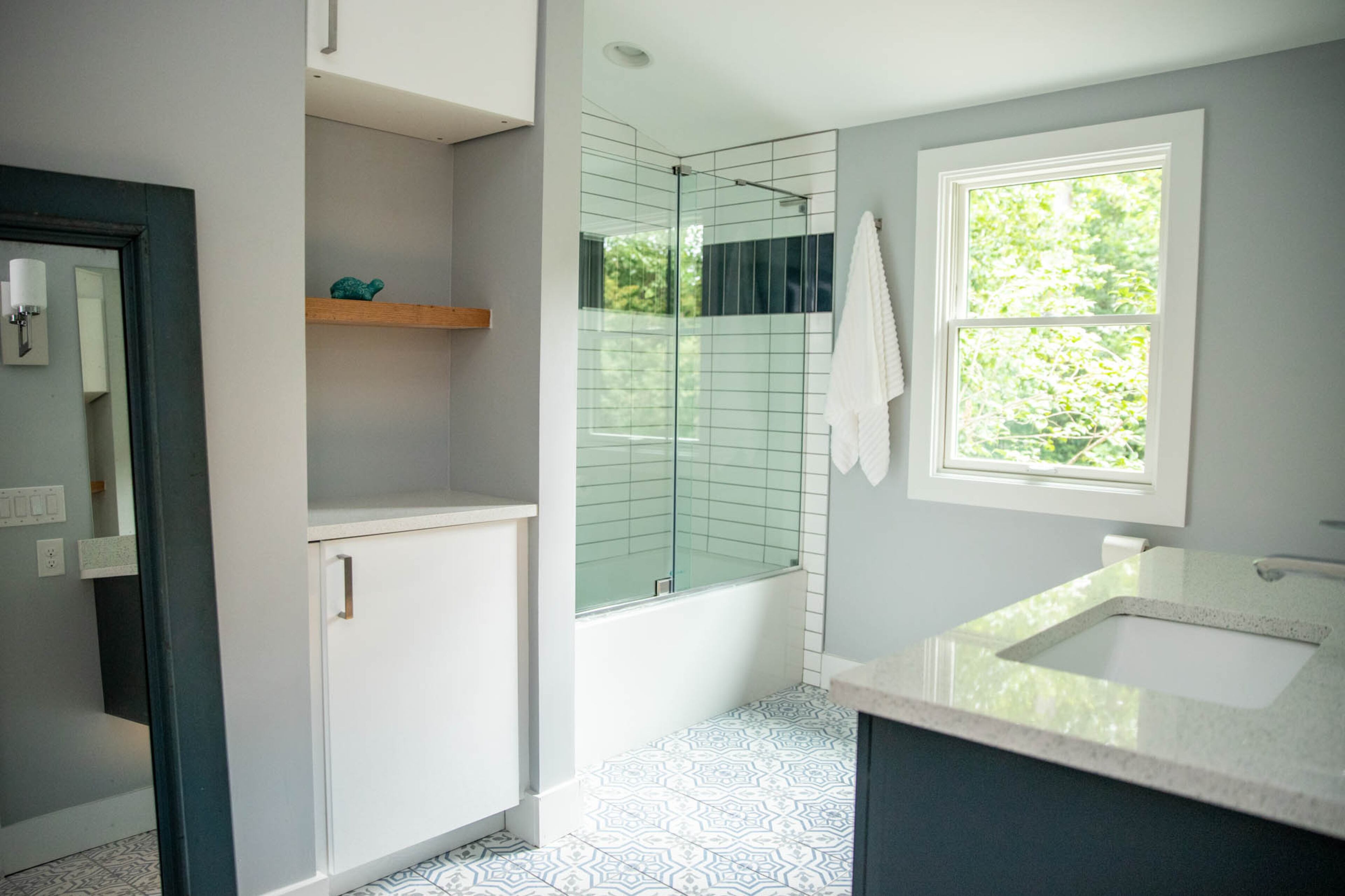 Breaking out of neutrals and adding a splash of pattern was a little outside of homeowners Adam Perry and Ben Ratossa's comfort zone, but they chose this stratford decorative porcelain tile from Floor & Decor for the floor in their upstairs guest bath. The blue of the floor compliments the dark navy floating vanity and the blue in the shower tiles from Floor & Decor. Another tiny turtle, this one from Finders Keepers Consignments, sits here on a shelf.