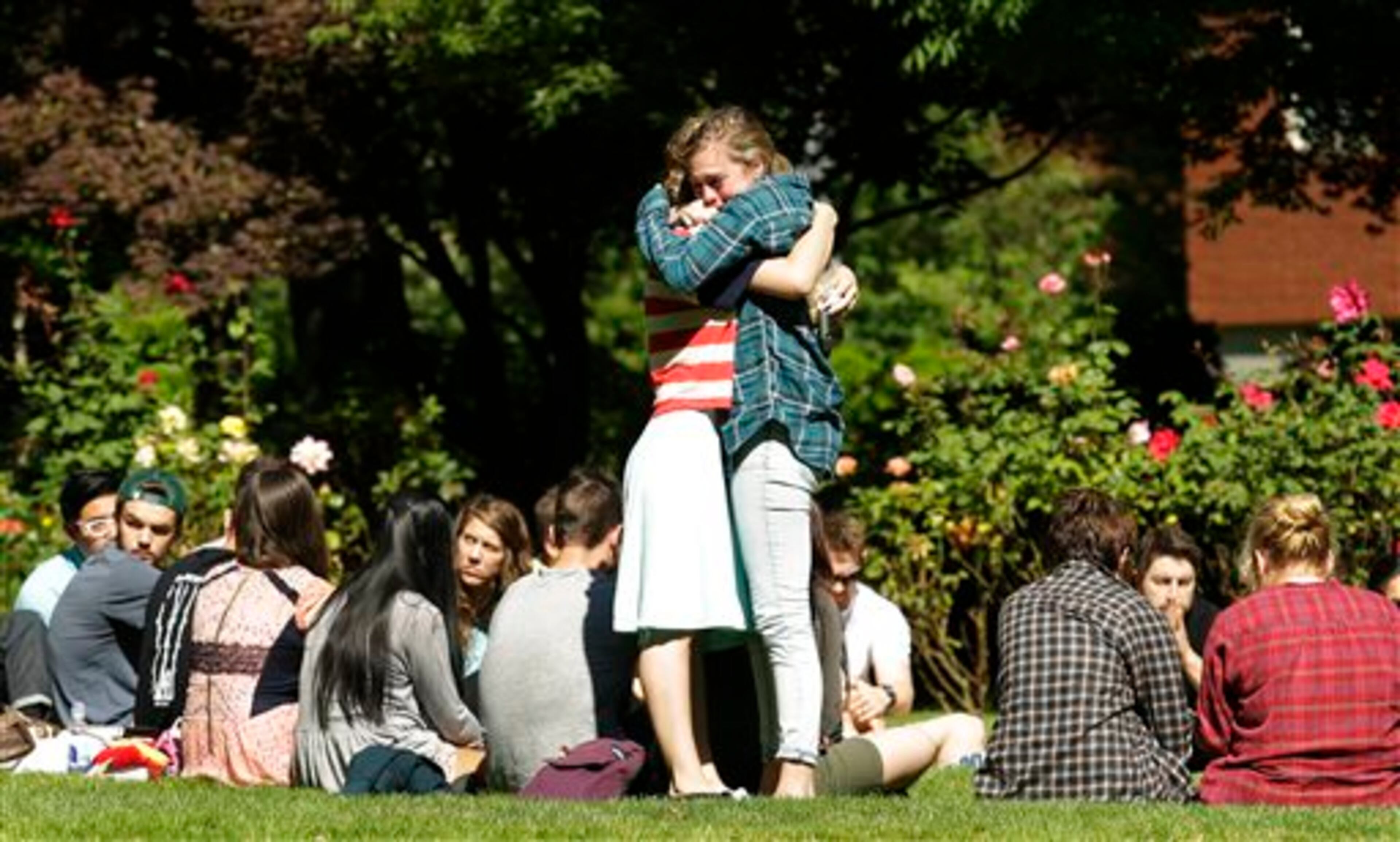Two women embrace near a prayer circle on the campus of Seattle Pacific University, Friday, June 6, 2014 in Seattle. Classes were canceled Friday following a shooting at Otto Miller Hall Thursday afternoon. A 19-year-old man was fatally shot and two other young people were wounded after a gunman entered the foyer and started shooting. Aaron R. Ybarra, 26, was booked into the King County Jail late Thursday for investigation of homicide, according to police and the jail roster. (AP Photo/Ted S. Warren)