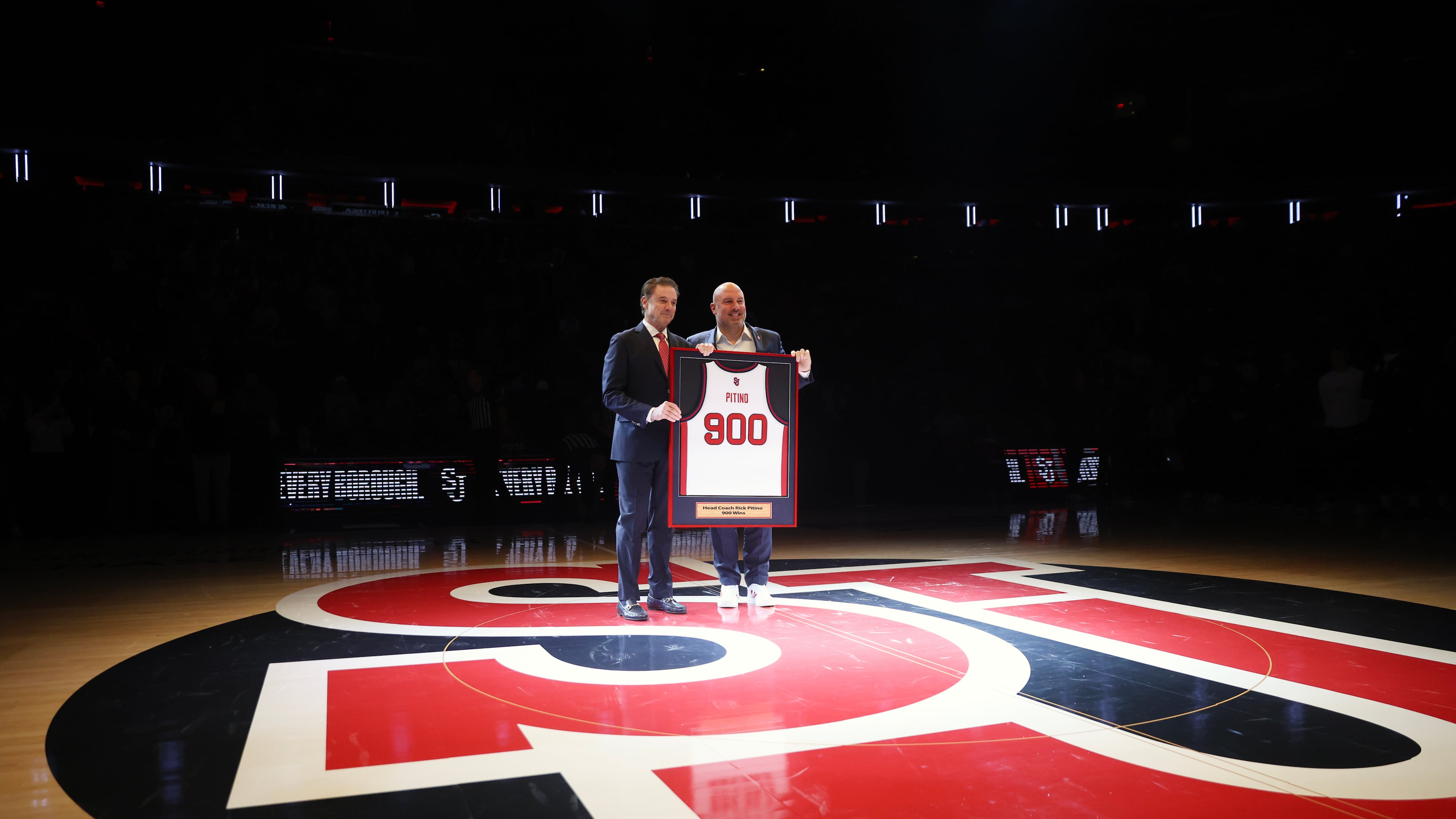 St. John's head coach Rick Pitino, left, is presented with a jersey by Ed Kull for his 900th win before an NCAA college basketball game against Butler, Wednesday, Jan. 28, 2026, in New York. (AP Photo/Heather Khalifa)
