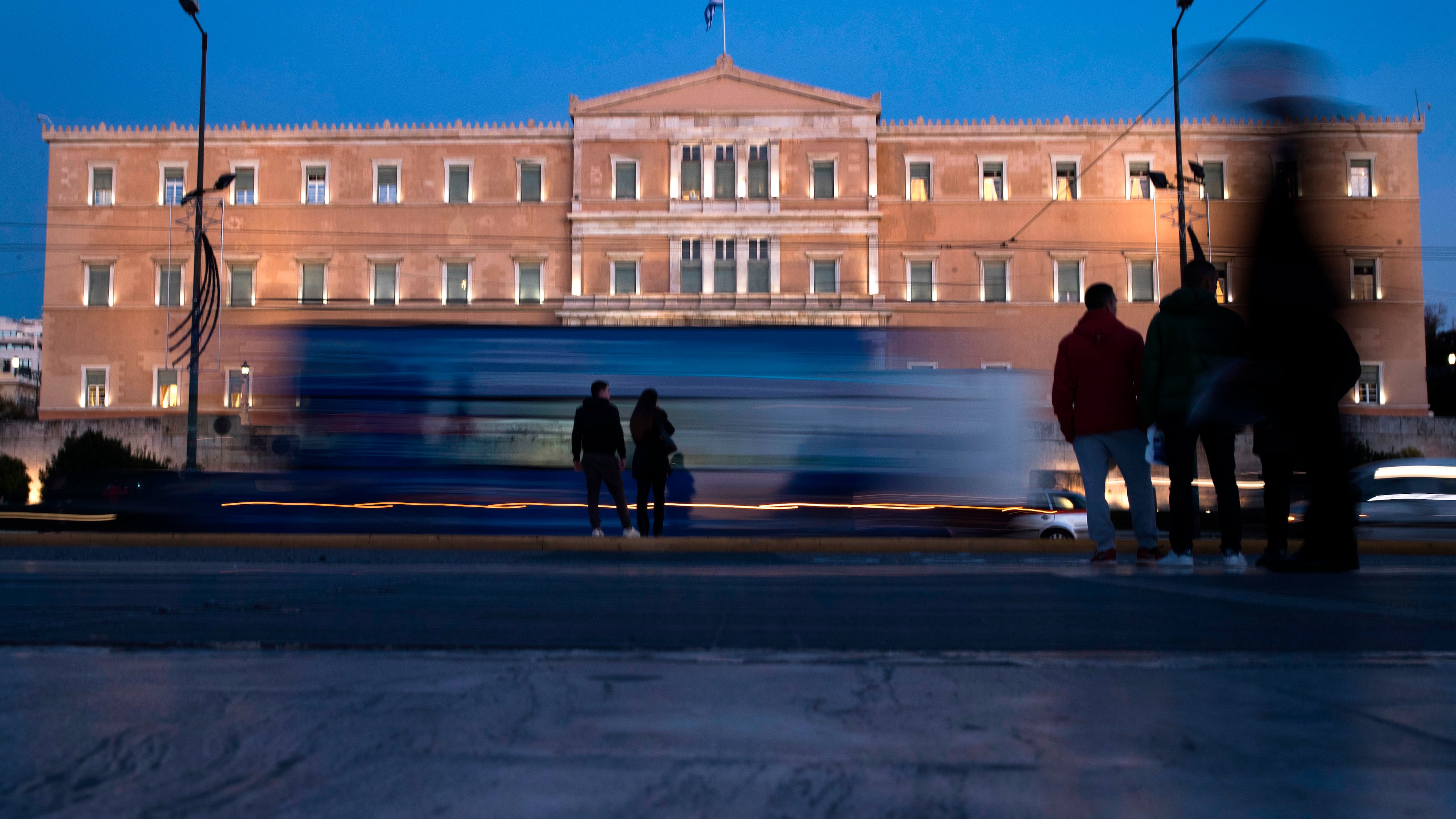 FILE - People stand in front of the Greek Parliament as vehicles drive past in central Athens, on Nov. 21, 2017. (AP Photo/Petros Giannakouris, File)