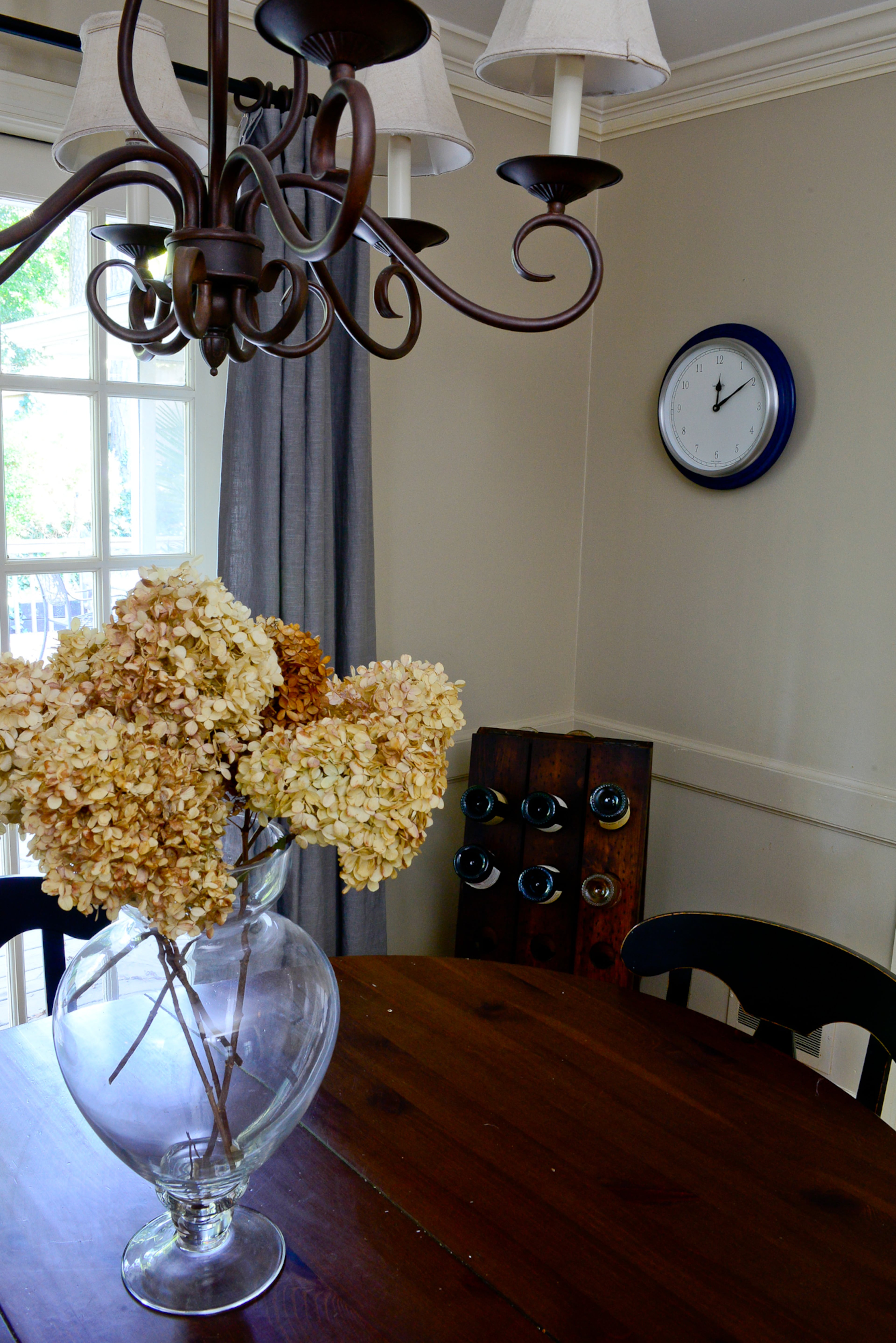 Craigslist bargains include a Pottery Barn table and chairs, now used for their eat-in kitchen and main dining area. The corner wood wine rack is from Z Gallerie, and the chandelier was existing to the home.