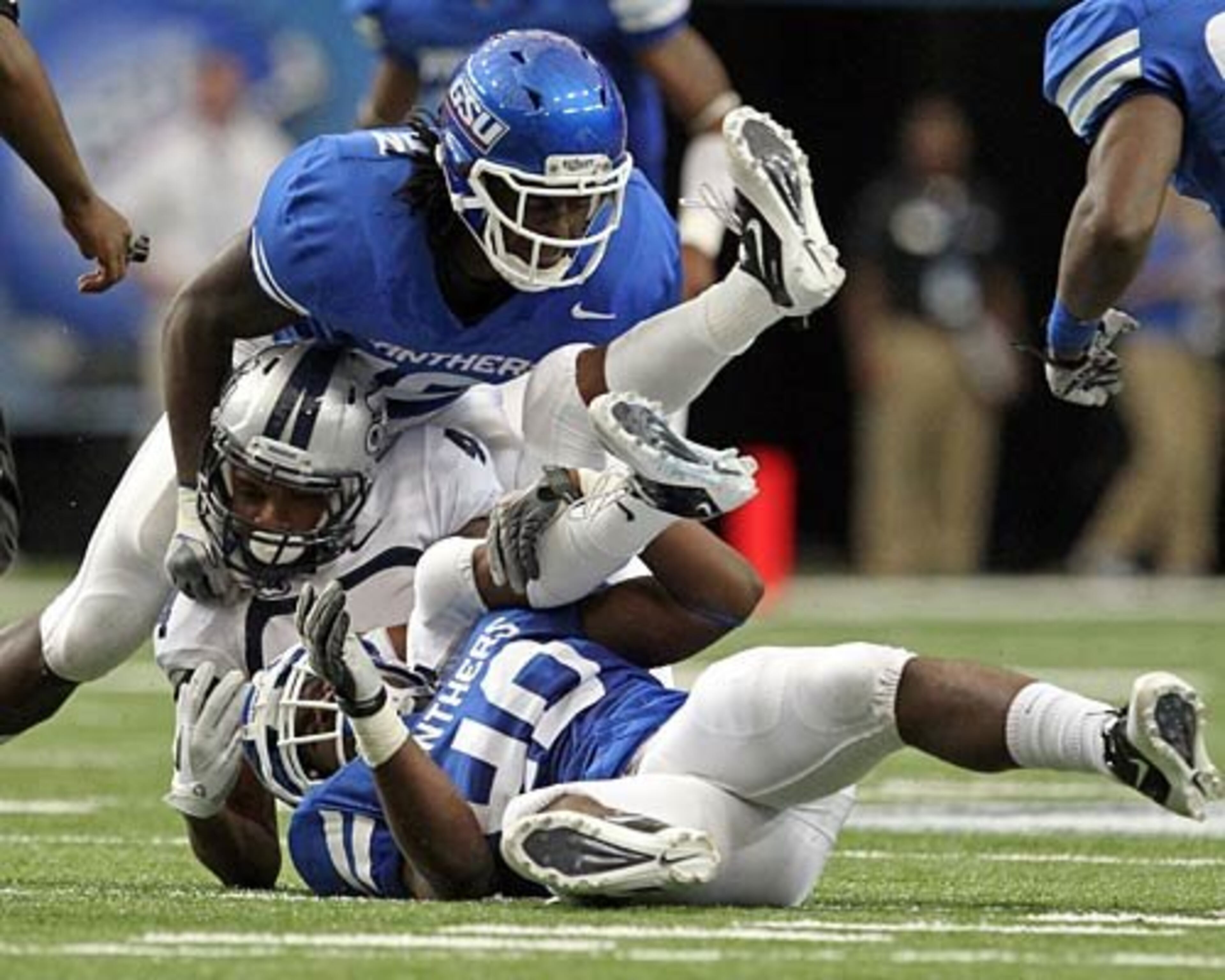 Old Dominion wide receiver Reid Evans, center, gets twisted after a catch as Georgia State defenders Robert Ferguson (10, top) and Qwontez Mallory (40, bottom) make the tackle.