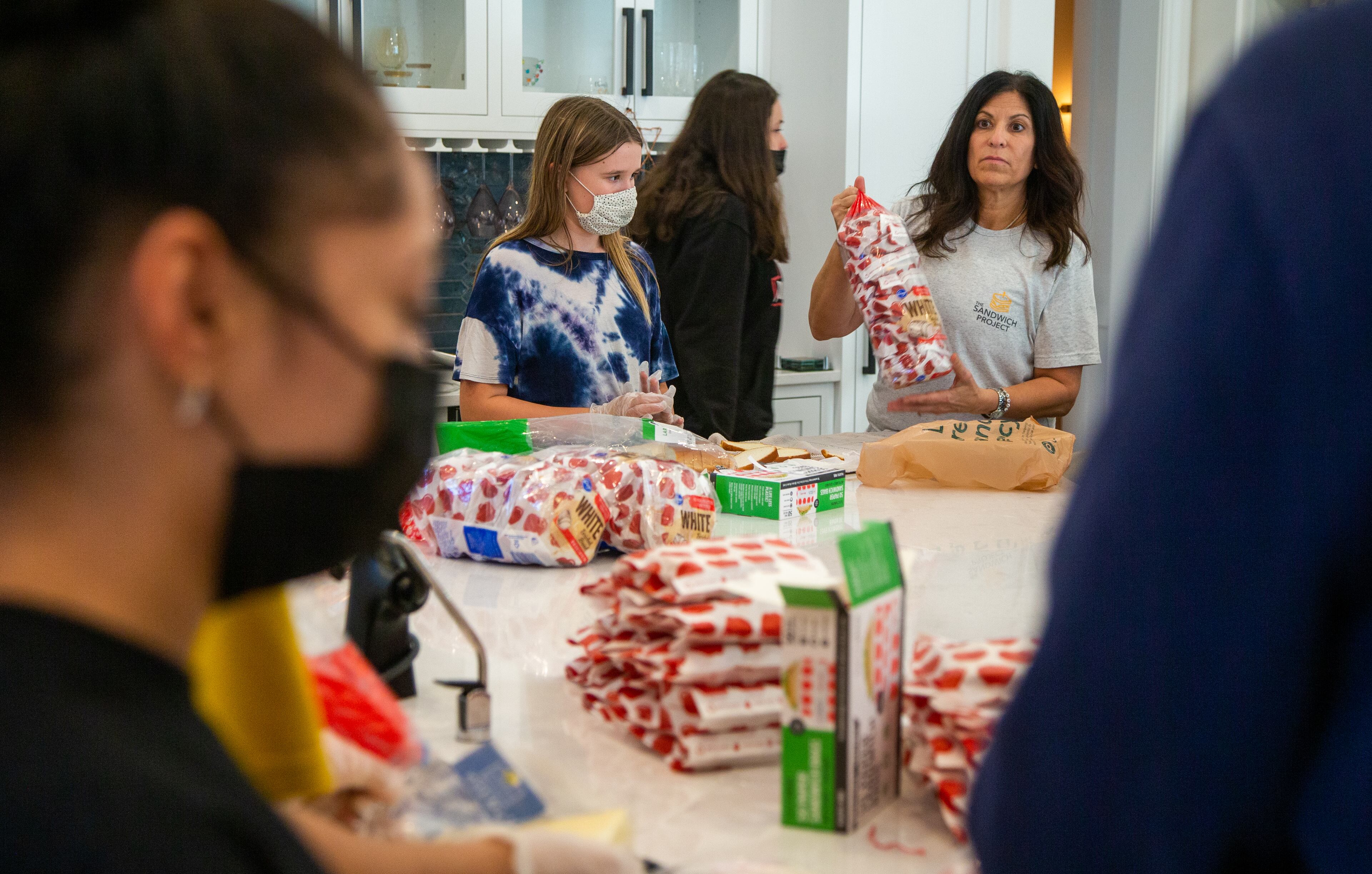Marcy Louza (right) directs a group of volunteers making sandwiches for The Sandwich Project. Two ladies from Dunwoody started making sandwiches for the homeless during the pandemic and this project has expanded into a weekly community service project involving thousands of volunteers all over the metro area. Every week, The Sandwich Project gives away approximately 4,000 to 6,000 sandwiches, plus snacks and fruit to nonprofits for distribution. PHIL SKINNER FOR THE ATLANTA JOURNAL-CONSTITUTION.