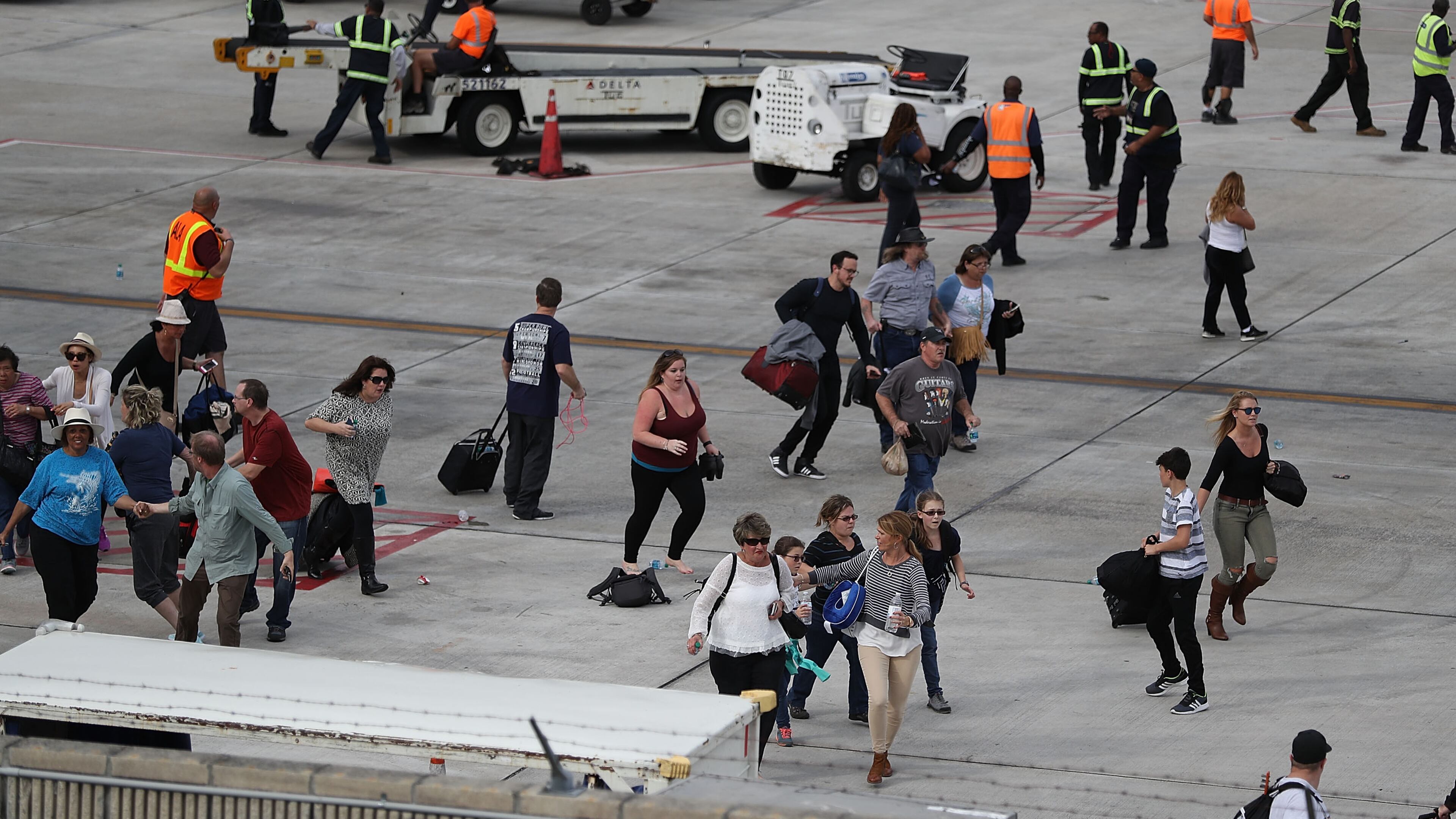 People seek cover on the tarmac of Fort Lauderdale-Hollywood International airport after a shooting took place near the baggage claim on January 6, 2017 in Fort Lauderdale, Florida. Officials are reporting that five people were killed and eight wounded in an attack by a single gunman. (Photo by Joe Raedle/Getty Images)