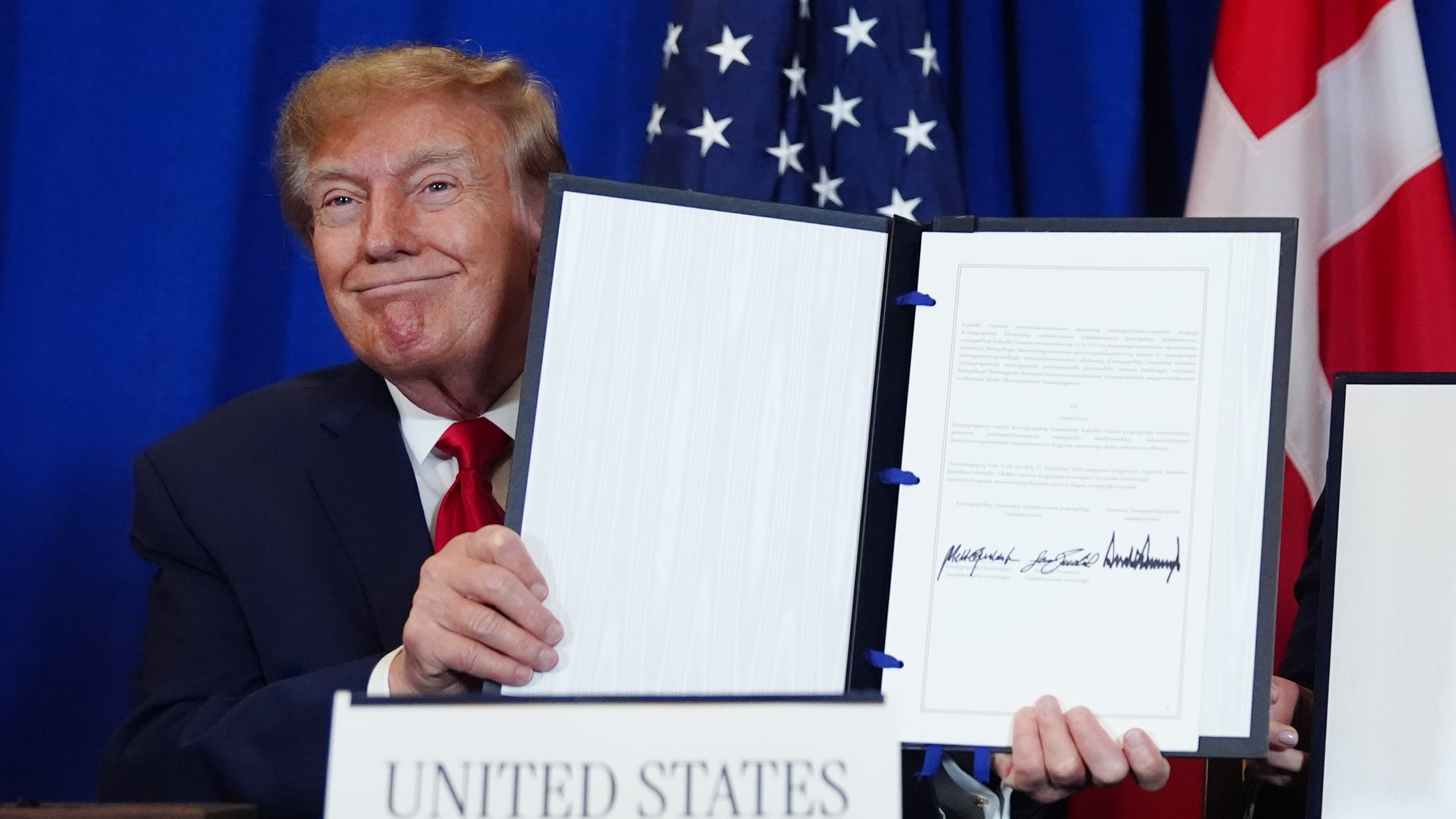 President Donald Trump holds up the document after signing a security agreement with Denmark's Prime Minister Mette Frederiksen and Greenland's Prime Minister Jens-Frederik Nielsen during the United Nations General Assembly, Tuesday, Sept. 22, 2026, at the UN headquarters. (AP Photo/Julia Demaree Nikhinson)