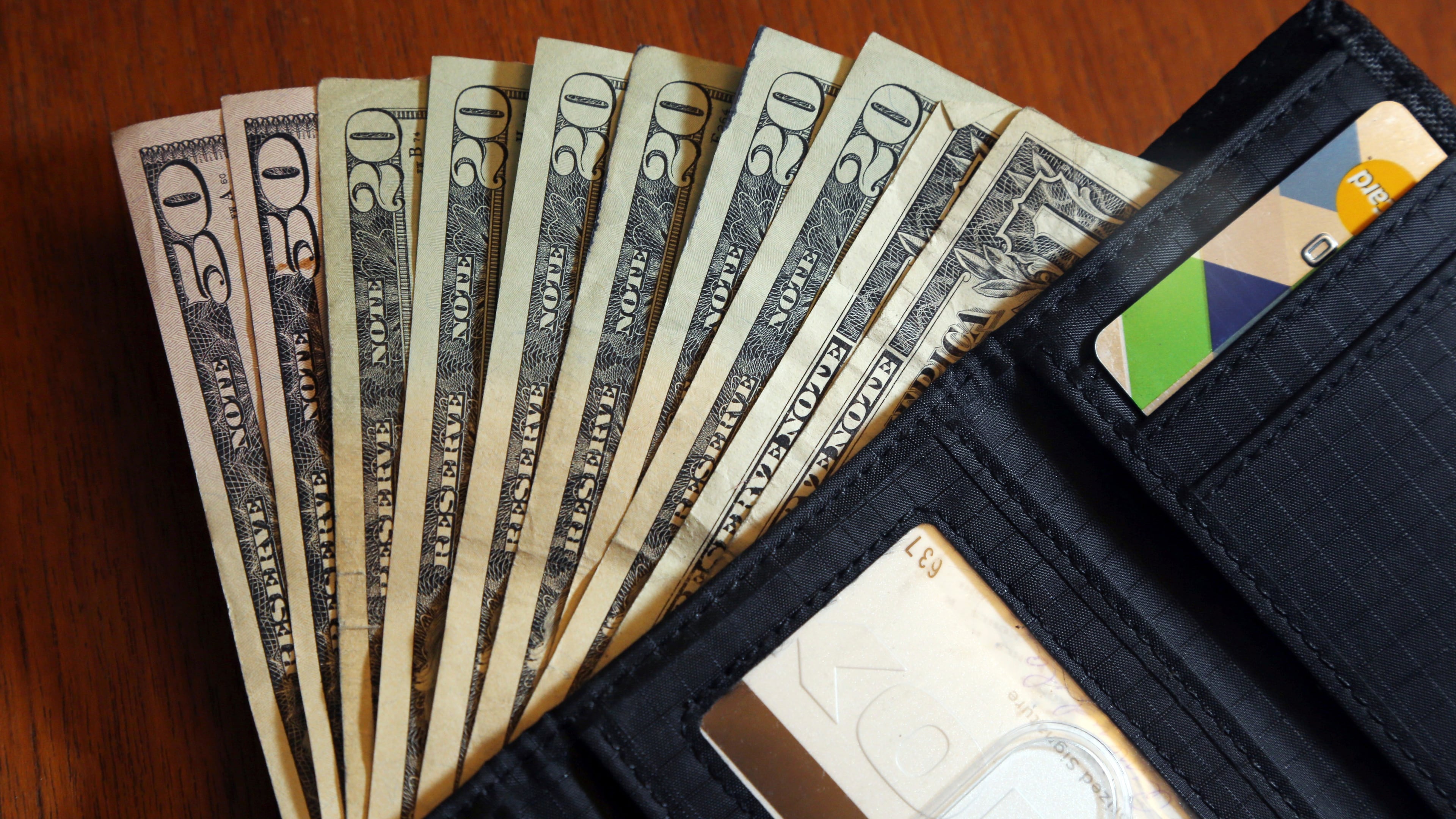 FILE - Cash is fanned out from a wallet in North Andover, Mass, June 15, 2018. (AP Photo/Elise Amendola, File)