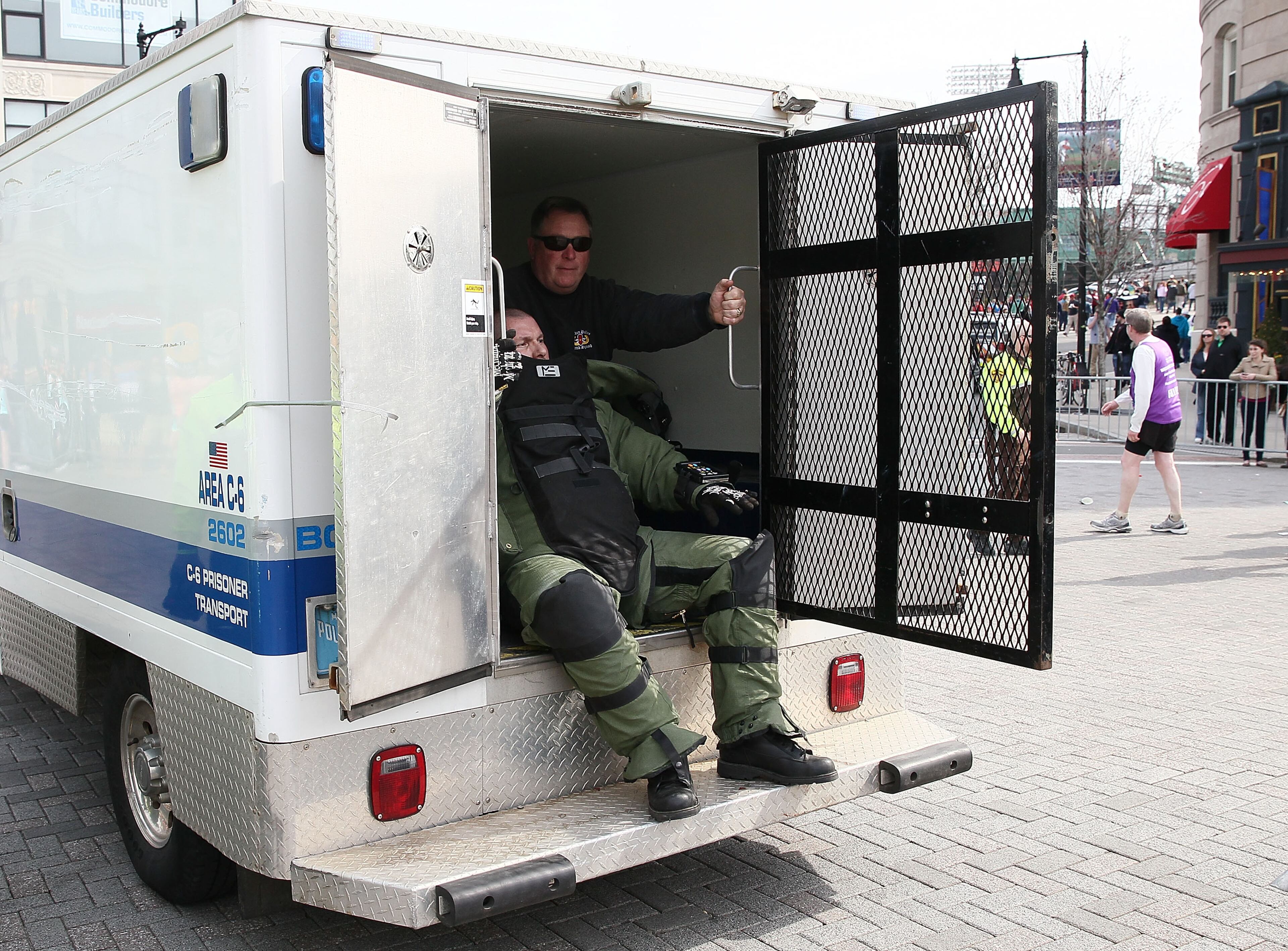 BOSTON, MA - APRIL 15: Members of the bomb squad prepare investigate a suspicious item on the road as runners pass near Kenmore Square after two bombs exploded during the 117th Boston Marathon on April 15, 2013 in Boston, Massachusetts. Two people are confirmed dead and at least 28 injured after at least two explosions went off near the finish line to the marathon. (Photo by Alex Trautwig/Getty Images)