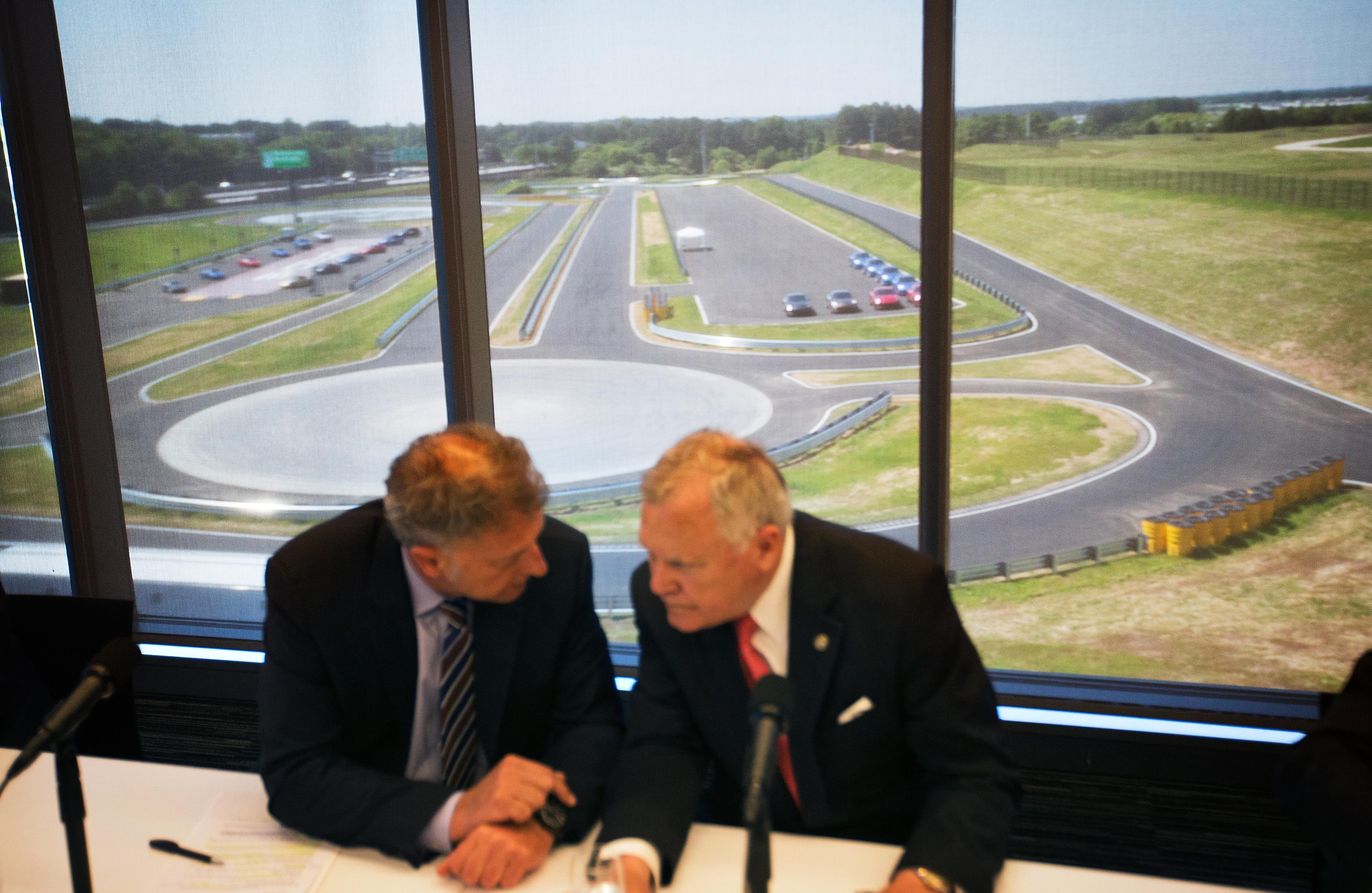 A driver development track is seen in the background as Georgia Gov. Nathan Deal, right, talks with Detlev von Platen, president and CEO of Porsche Cars North America, left, before a press conference for the opening of the company's new North American headquarters, dubbed the Porsche Experience Center, Thursday, May 7, 2015, in Atlanta. The 27-acre complex is located on the former site of a Ford Motor Co. assembly plant that was in production for almost 60 years at the edge of Hartsfield-Jackson Atlanta International Airport. It is the sports-car company's largest investment outside of Germany. (AP Photo/David Goldman)
