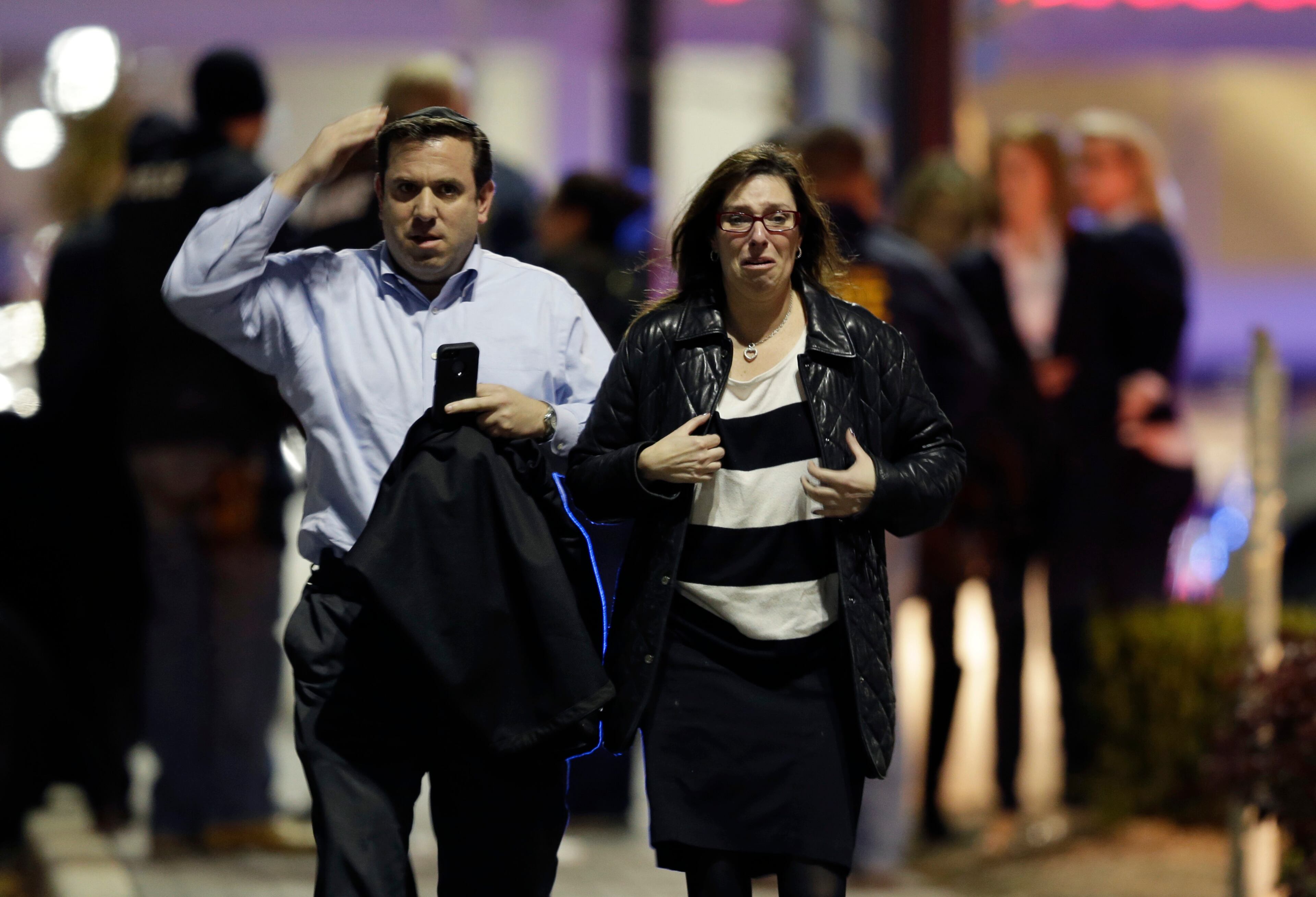 A man and woman leave the Garden State Plaza Mall with officials standing guard behind them following reports of a shooter, Monday, Nov. 4, 2013, in Paramus, N.J. Hundreds of law enforcement officers converged on the mall Monday night after witnesses said multiple shots were fired there. (AP Photo/Julio Cortez)