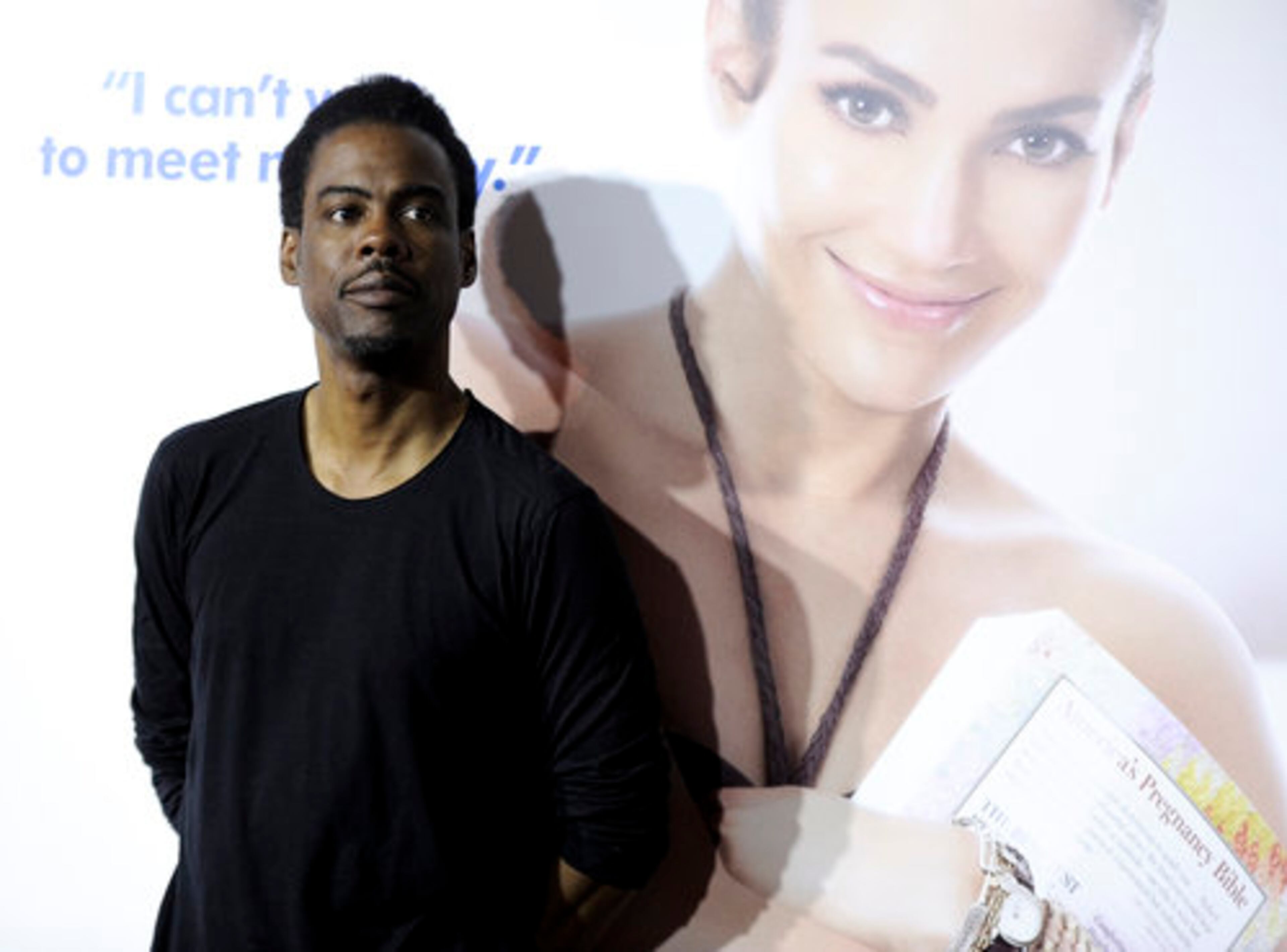 Co-star Chris Rock poses by a poster promoting the movie.
